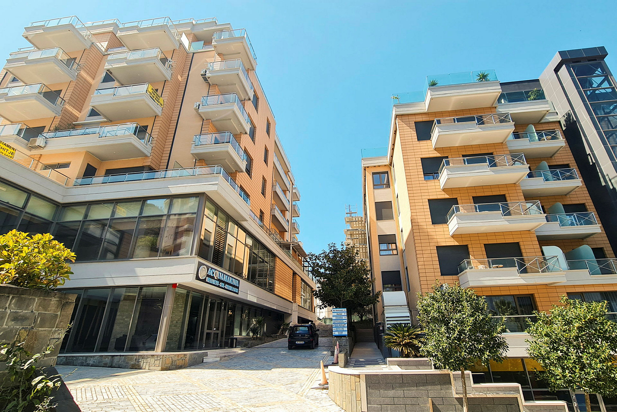 Höga bostadshus med balkonger och glasfasader under klarblå himmel. (AI-genererad text)