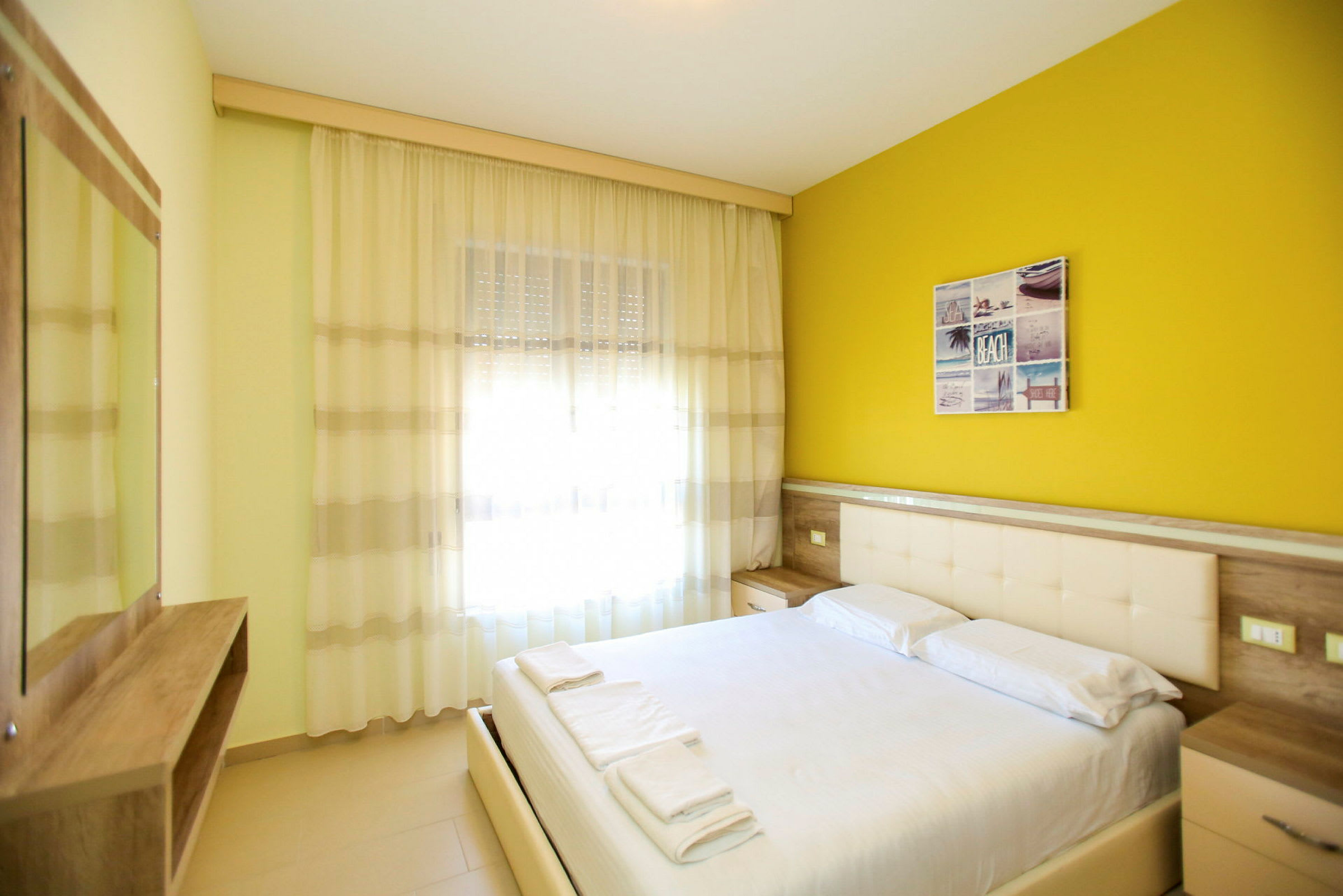 Ett hotellrum med en dubbelbädd och gul vägg. (AI-genererad text)