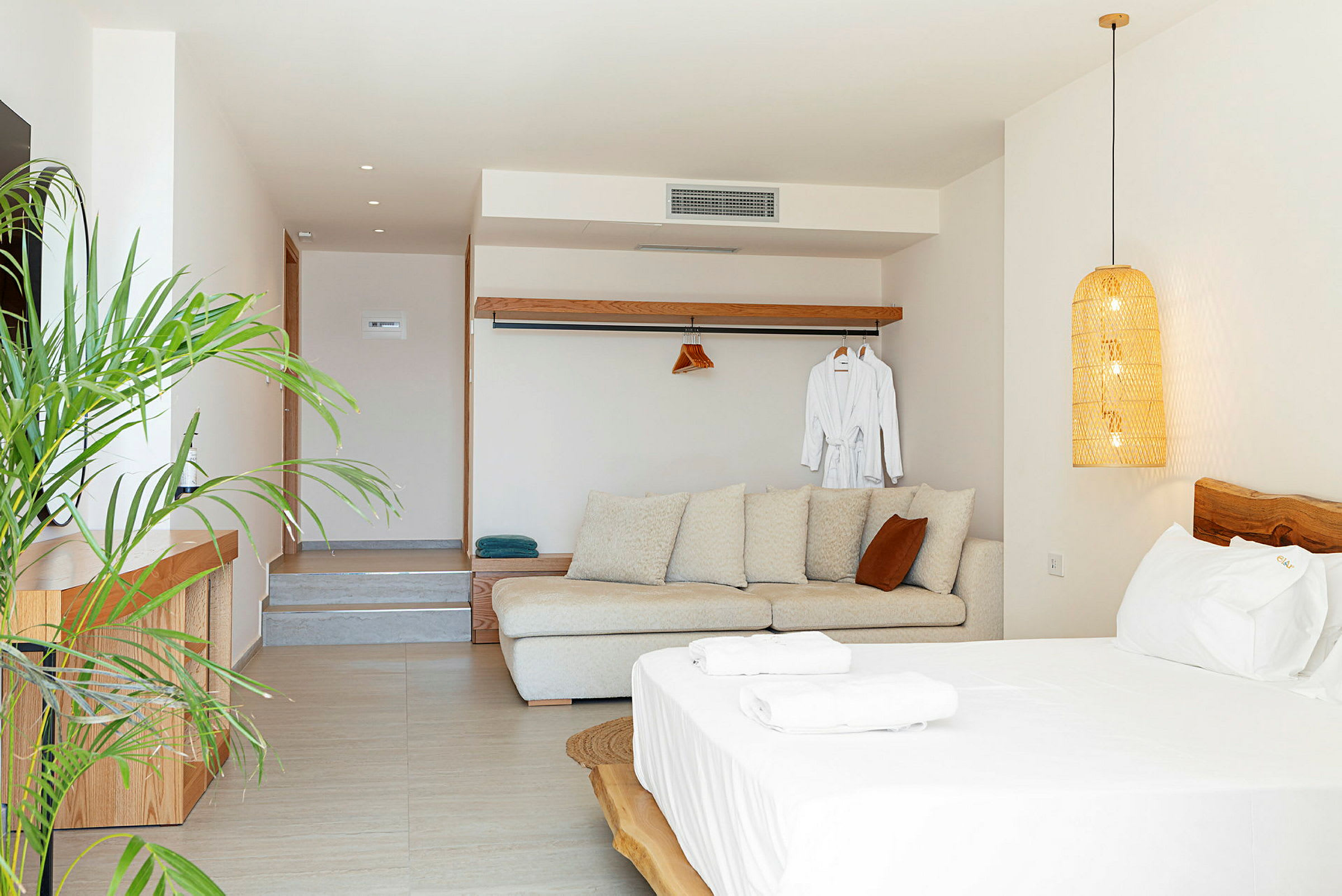 Ett ljust och modernt hotellrum med soffa, säng och växter. (AI-genererad text)