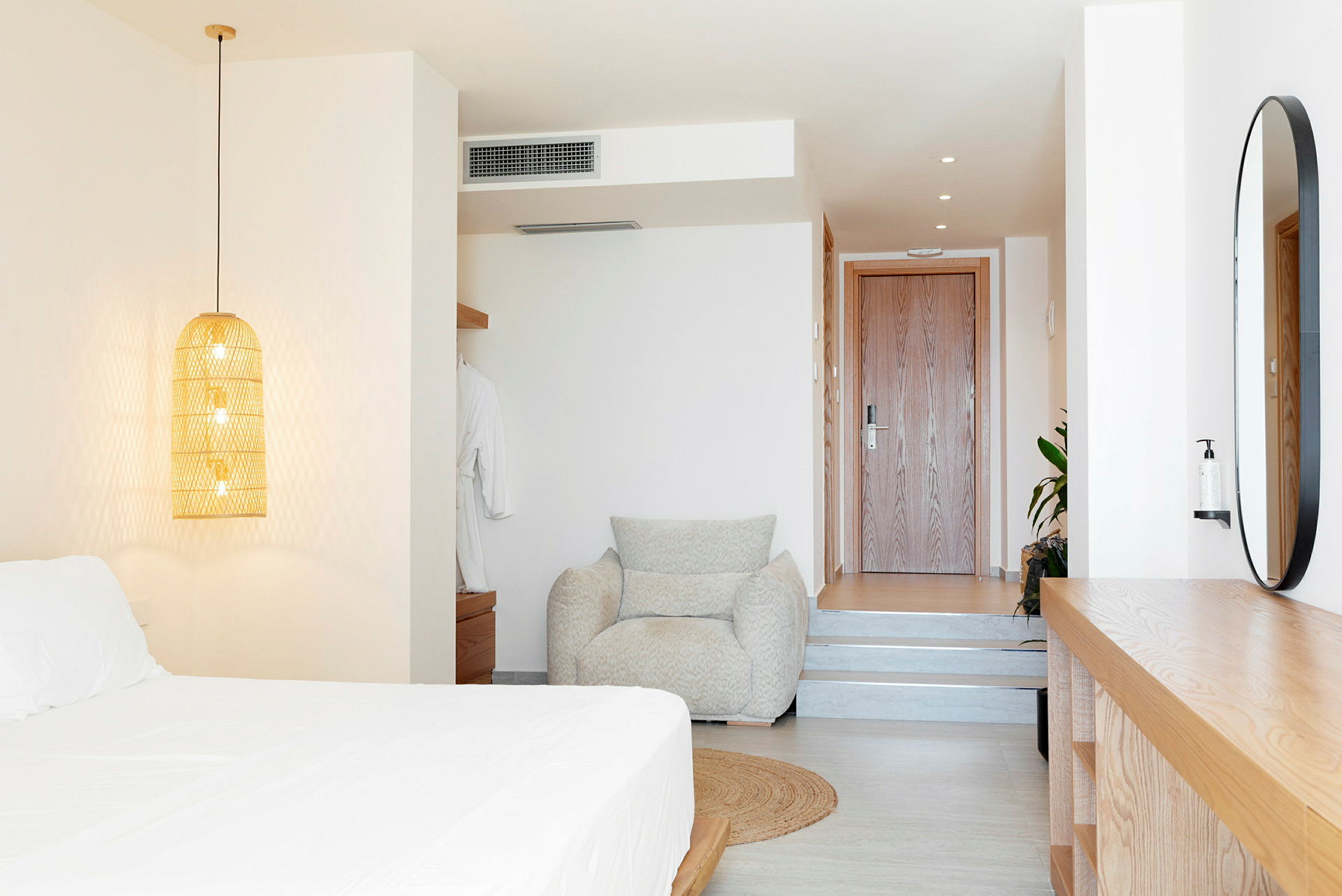 Modernt inrett hotellrum med säng, fåtölj och trädetaljer. (AI-genererad text)