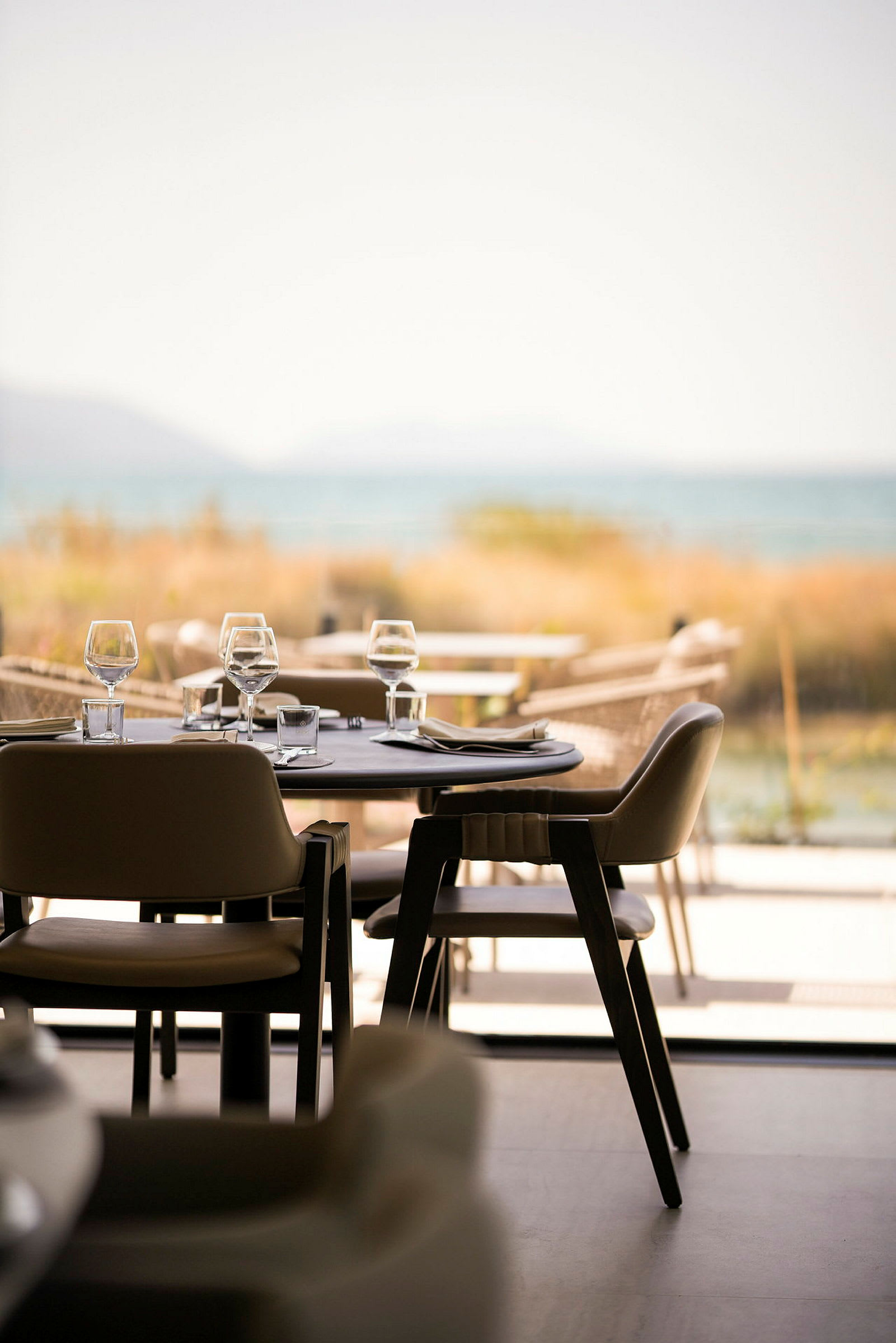 En elegant restaurang med dukade bord och stolar, med en utsikt mot havet. (AI-genererad text)