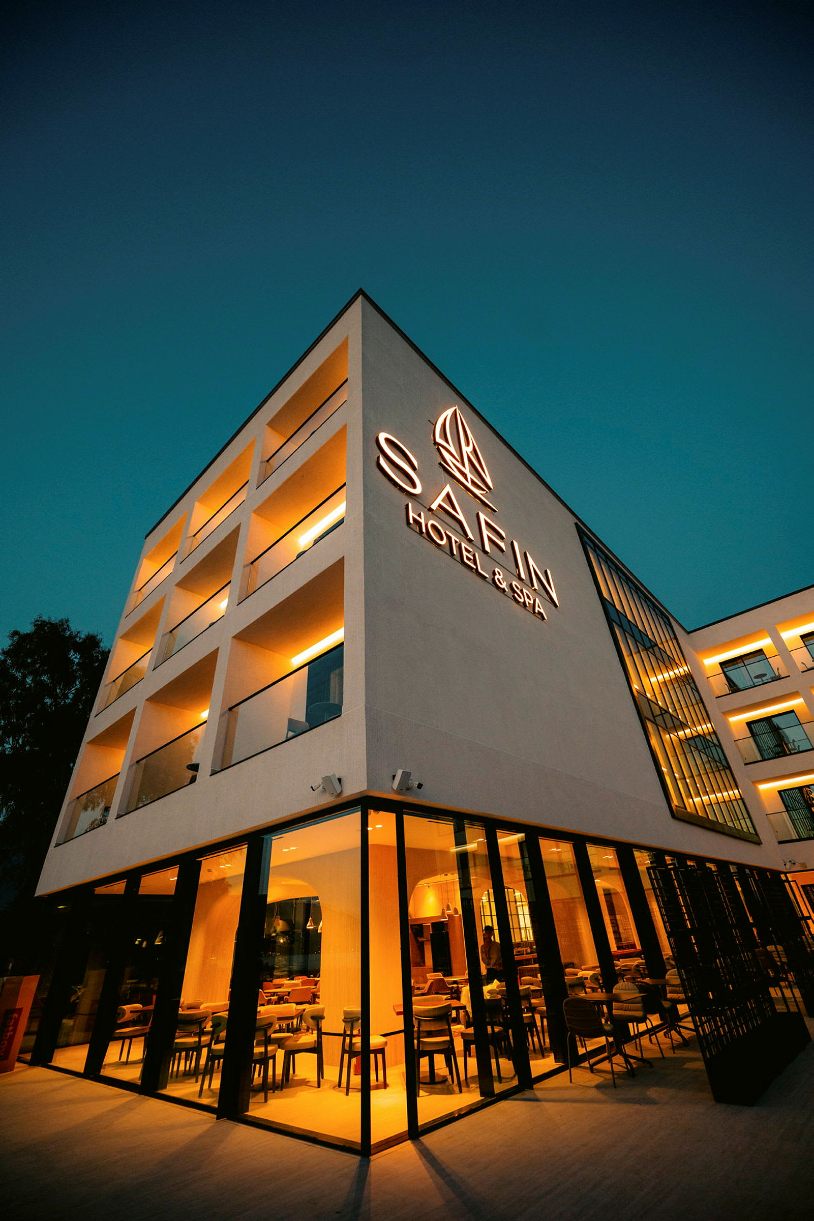 Fyrkantsformad byggnad upplyst på kvällen, märkt med texten "Safin Hotel & Spa". (AI-genererad text)