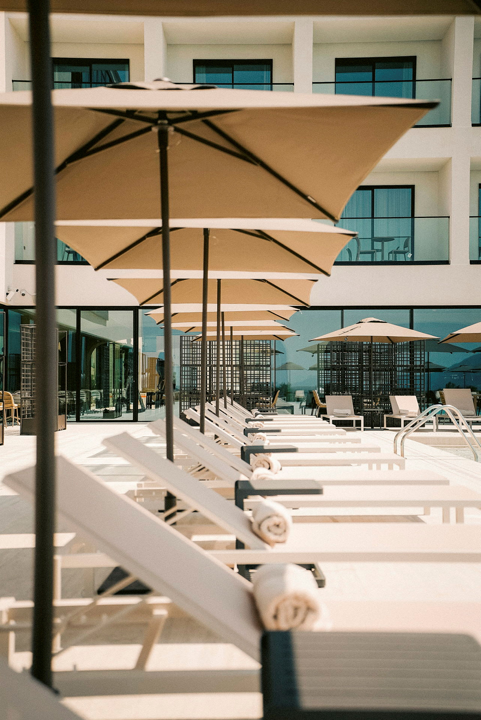 Solstolar och parasoller vid en pool framför en byggnad. (AI-genererad text)