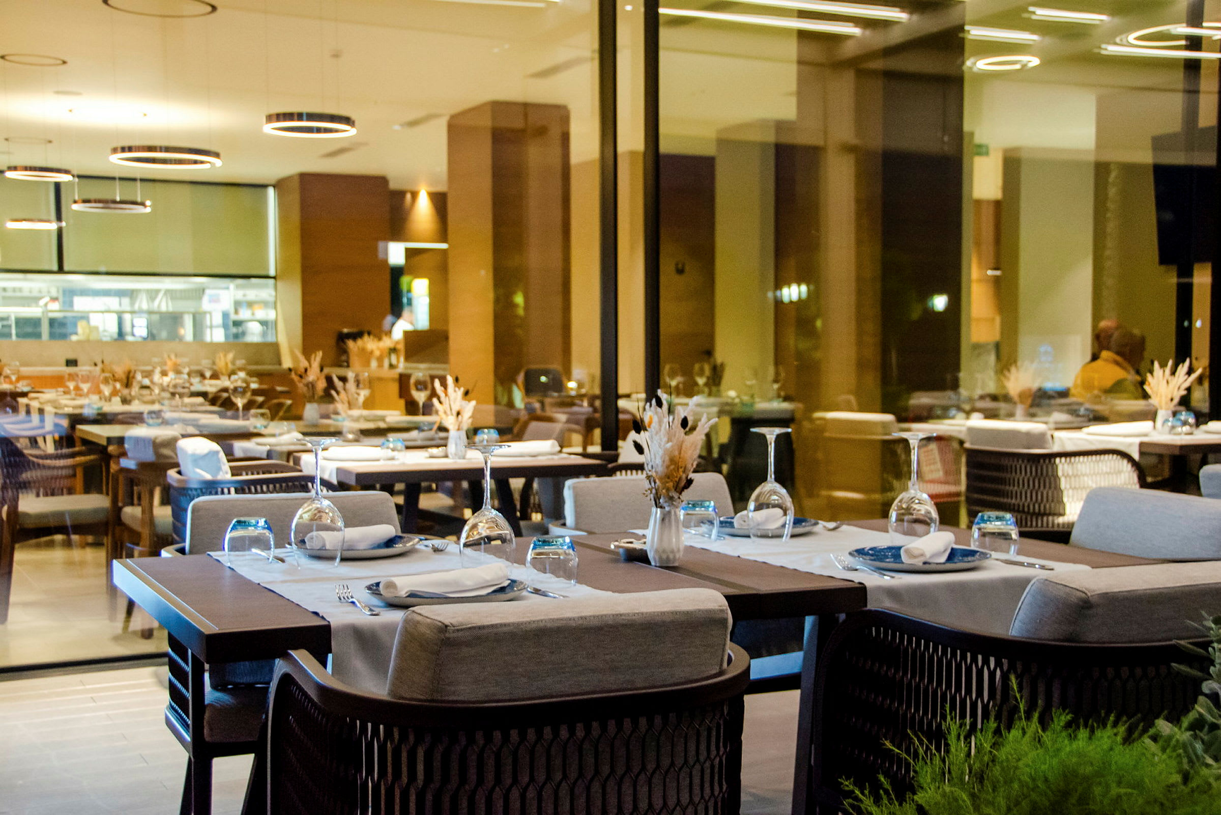 Bild på en modern restaurang med dukade bord och glasväggar. (AI-genererad text)