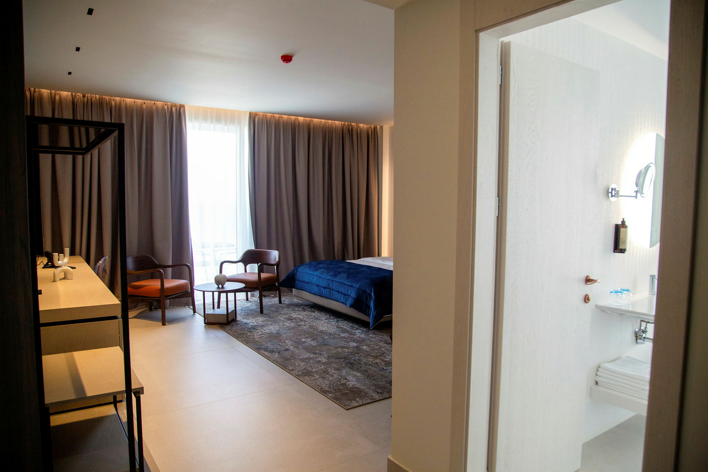 Hotellrum med säng, sittgrupp och skrivbord samt anslutande badrum. (AI-genererad text)