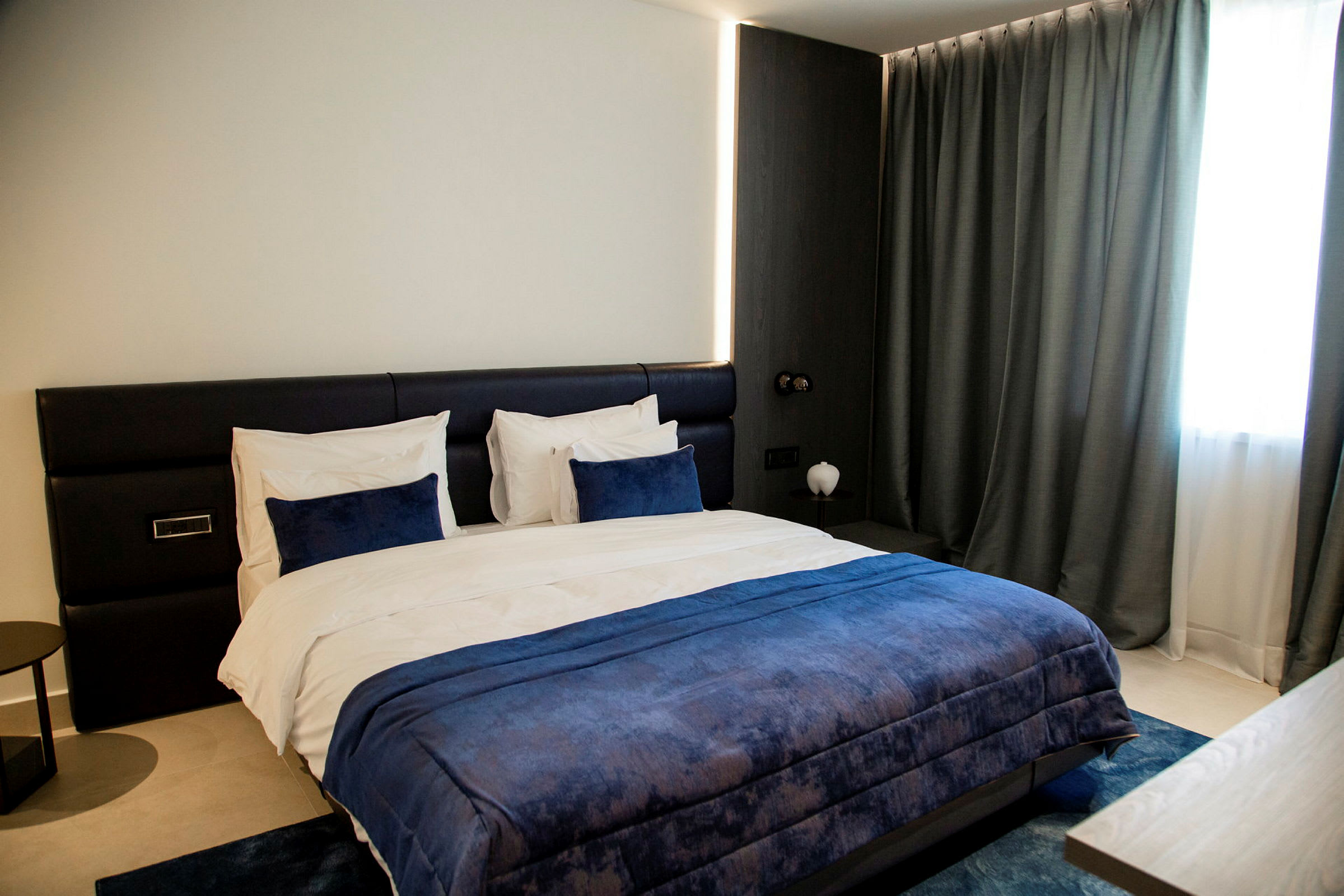 En modern hotellrum med en stor säng med blå sängkläder. (AI-genererad text)