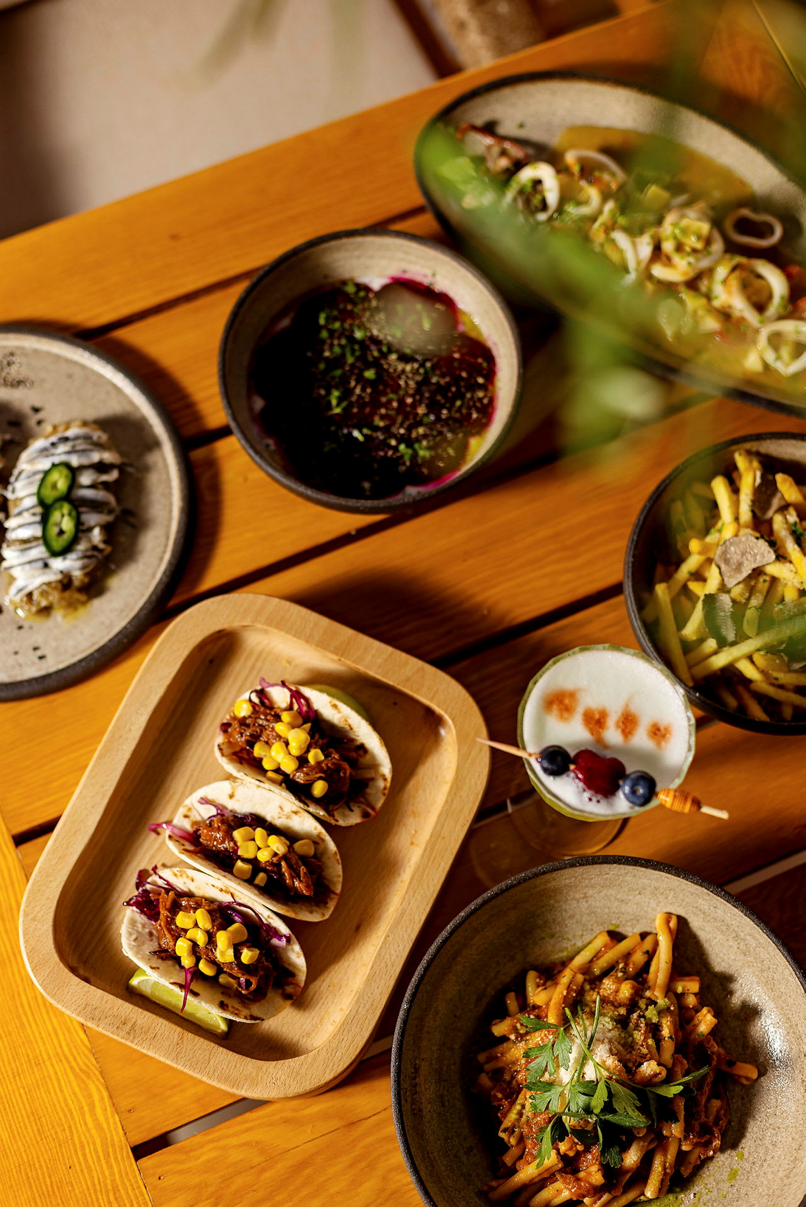 En träyta med ett urval av olika maträtter, inklusive tacos, pastarätt samt dryck. (AI-genererad text)