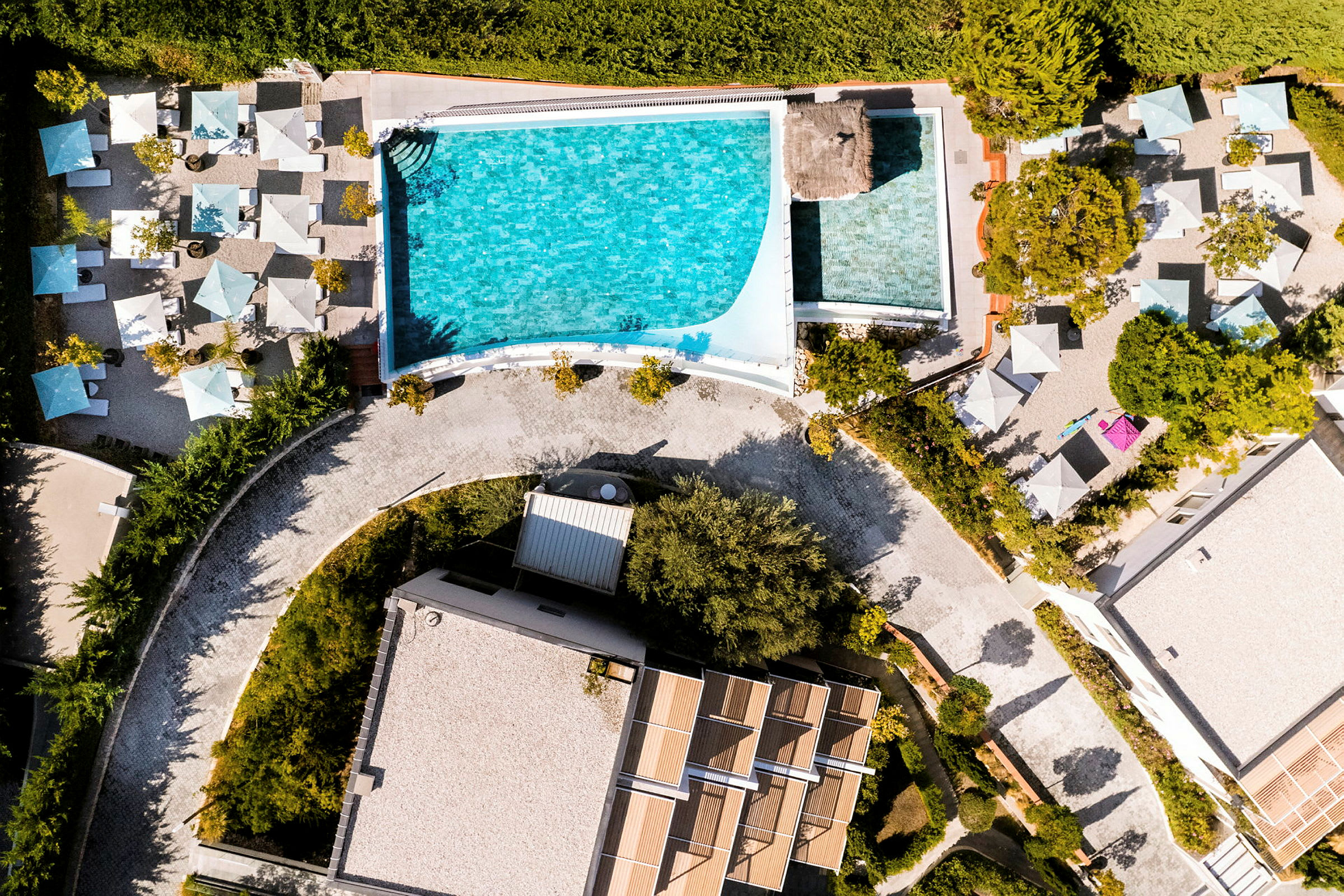 Flygbild av en pool med omgivande solstolar och parasoller. (AI-genererad text)