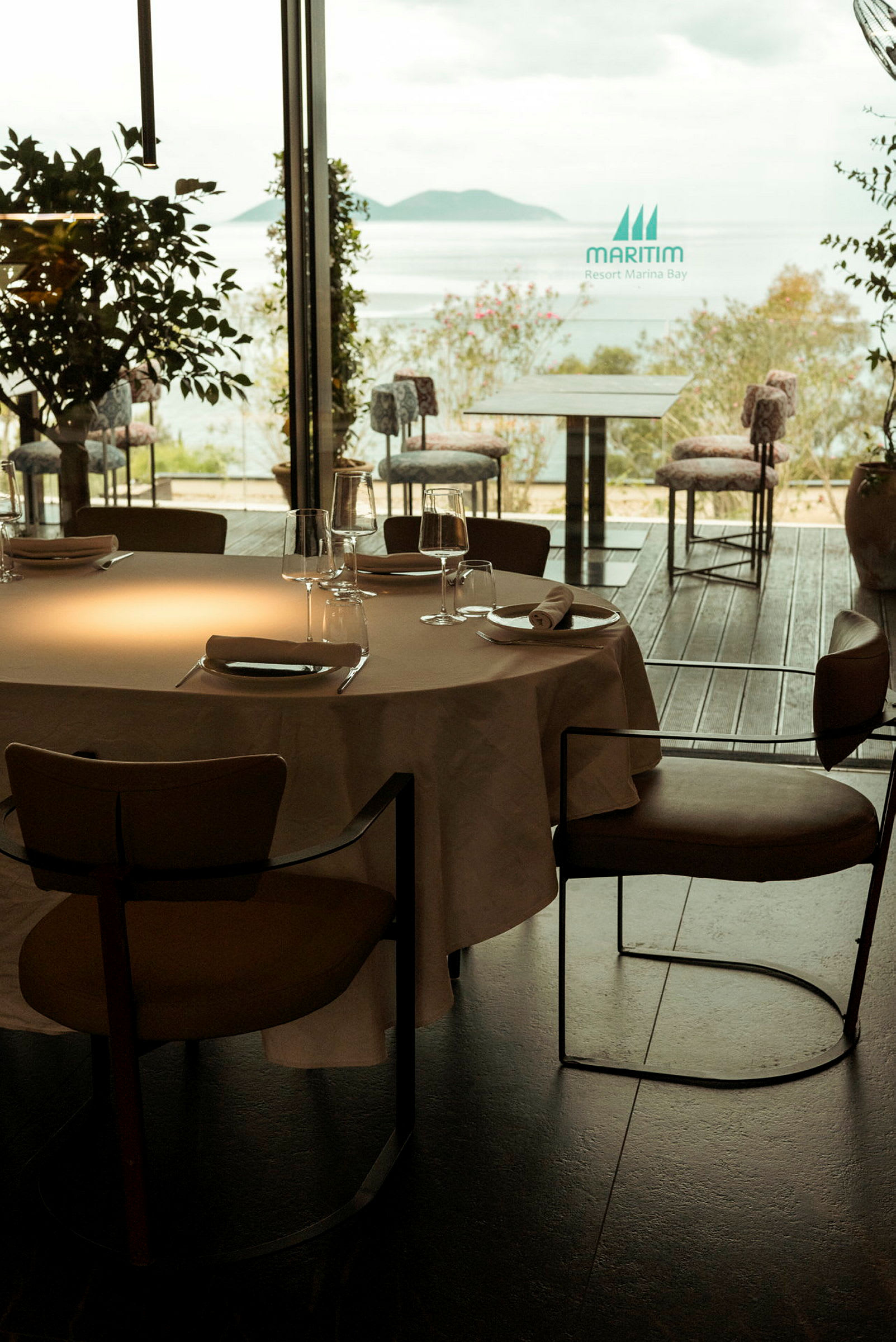 Ett bord med duk och glas på en restaurang med utsikt över havet. (AI-genererad text)