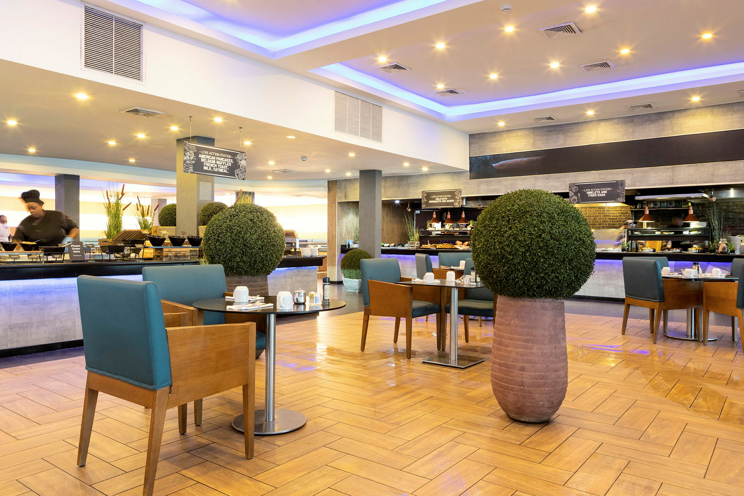 En modern hotellrestaurang med frukostbuffé och bord dekorerade med gröna växter. (AI-genererad text)