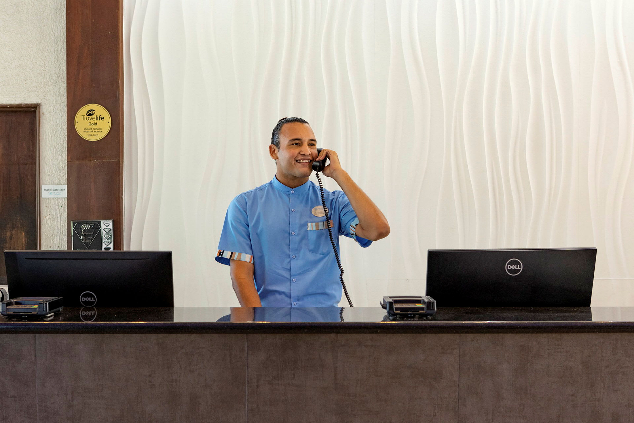 En person i en ljusblå uniform står bakom receptionsdisken och pratar i telefon. (AI-genererad text)