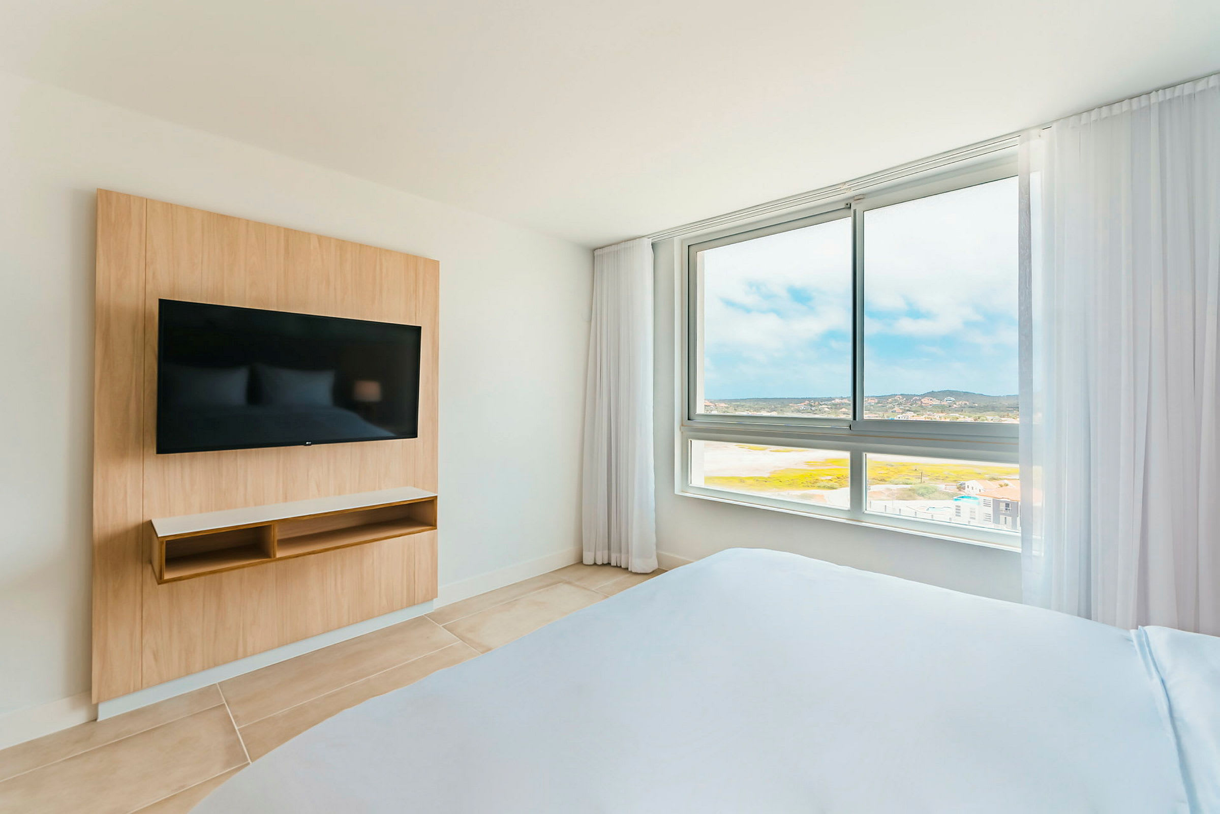 Hotellrum med en TV på väggen och en utsikt genom ett stort fönster. (AI-genererad text)