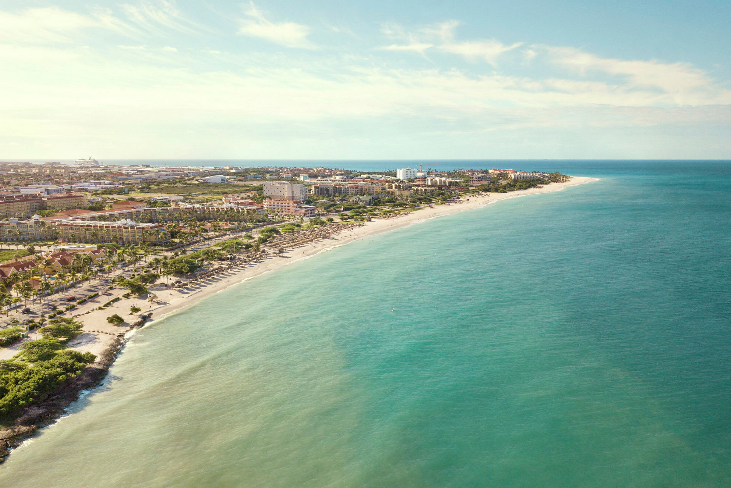 Strand med solstolar vid en kust med hotell och byggnader i bakgrunden. (AI-genererad text)