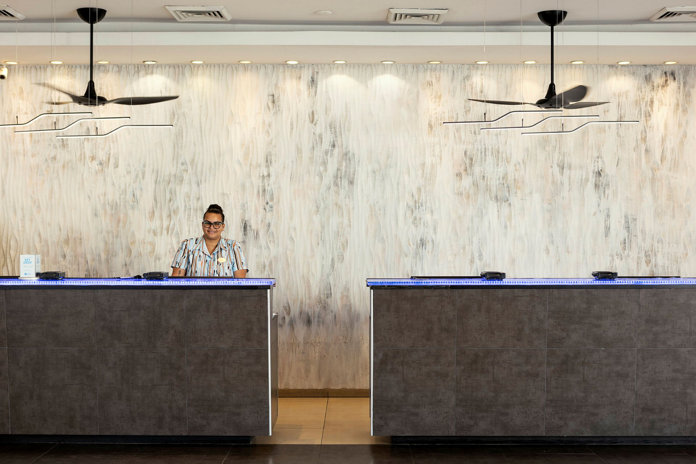 Reception med två diskar i ett hotell, dekorerad med moderna lampor och en ljus vägg. (AI-genererad text)