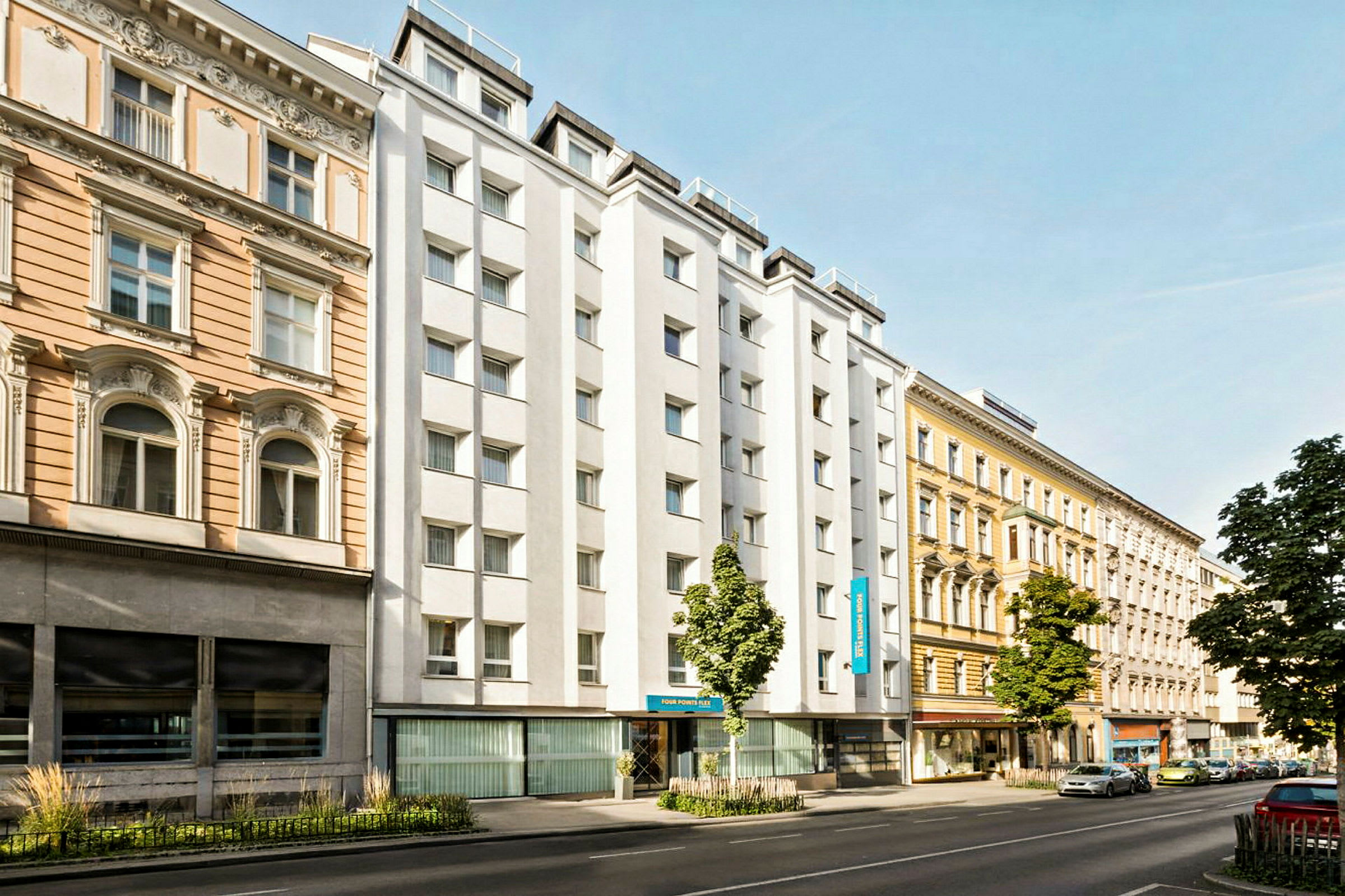 En stadsgata med byggnader från olika årtionden, inklusive ett hotell med vit fasad. (AI-genererad text)