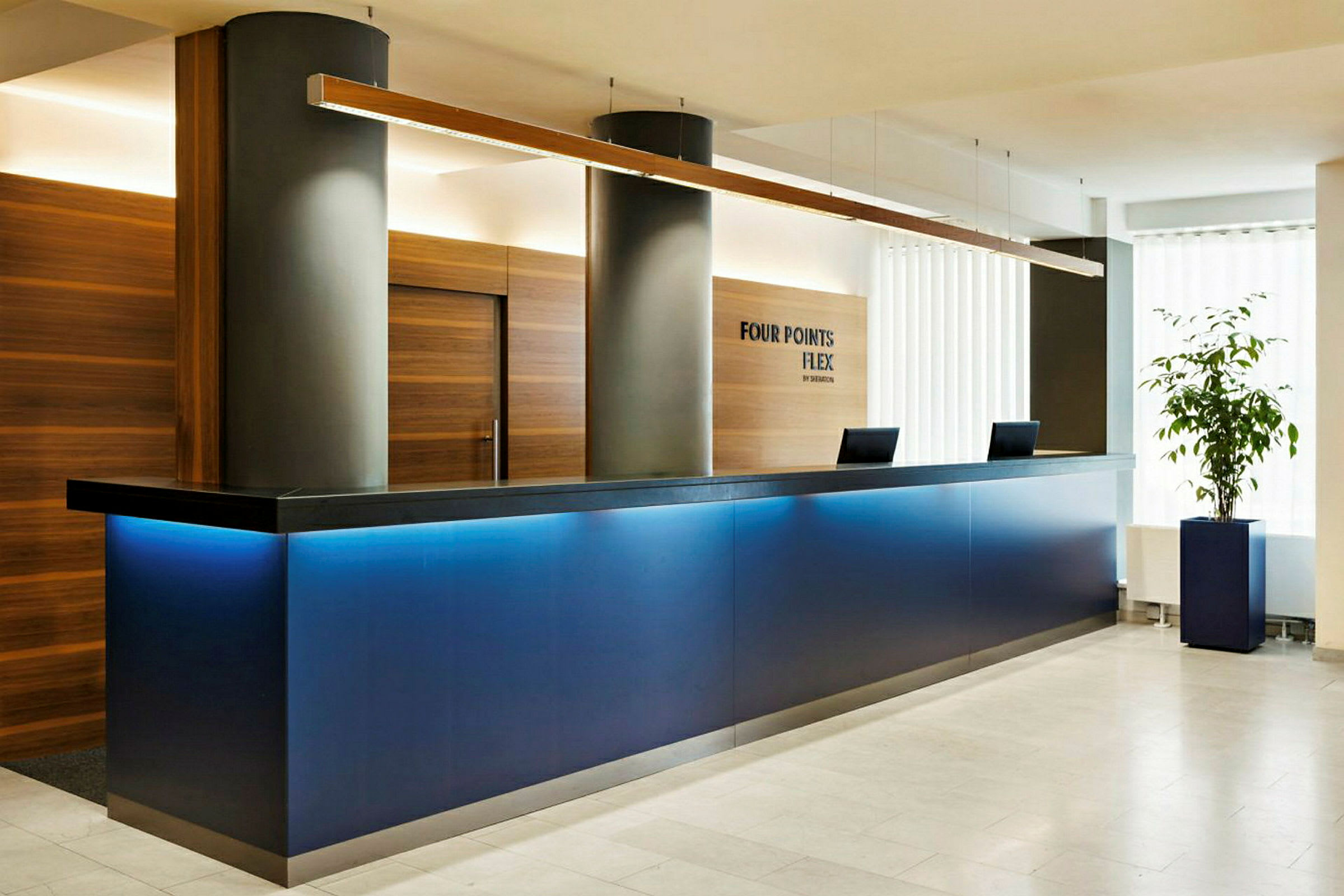 En reception med en blå dis och två datorer på bänken. En växt står till höger. (AI-genererad text)