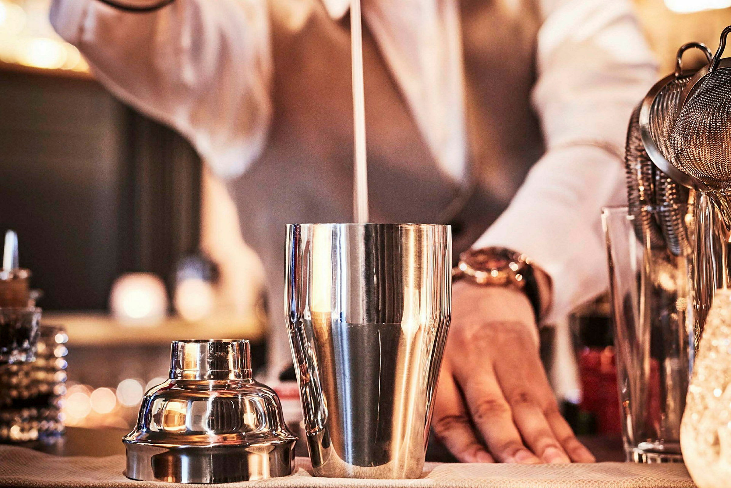 En bartender skakar en cocktail i en metalldrink-shaker. (AI-genererad text)