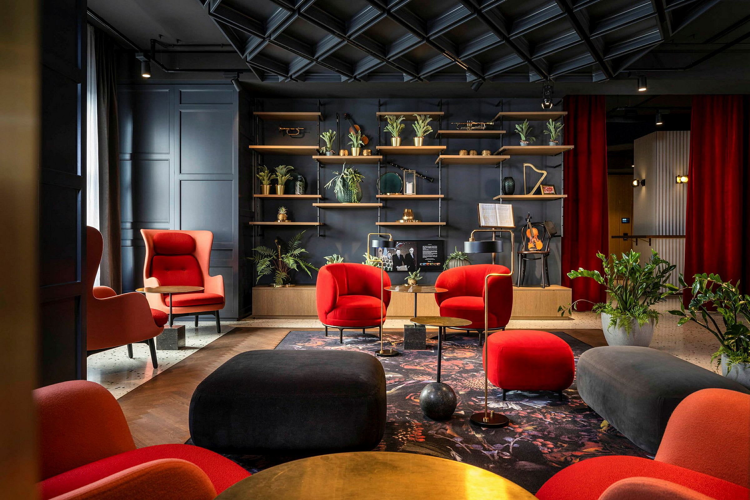 Elegant lounge med röda och svarta möbler, växter och en hylla med dekorativa föremål. (AI-genererad text)