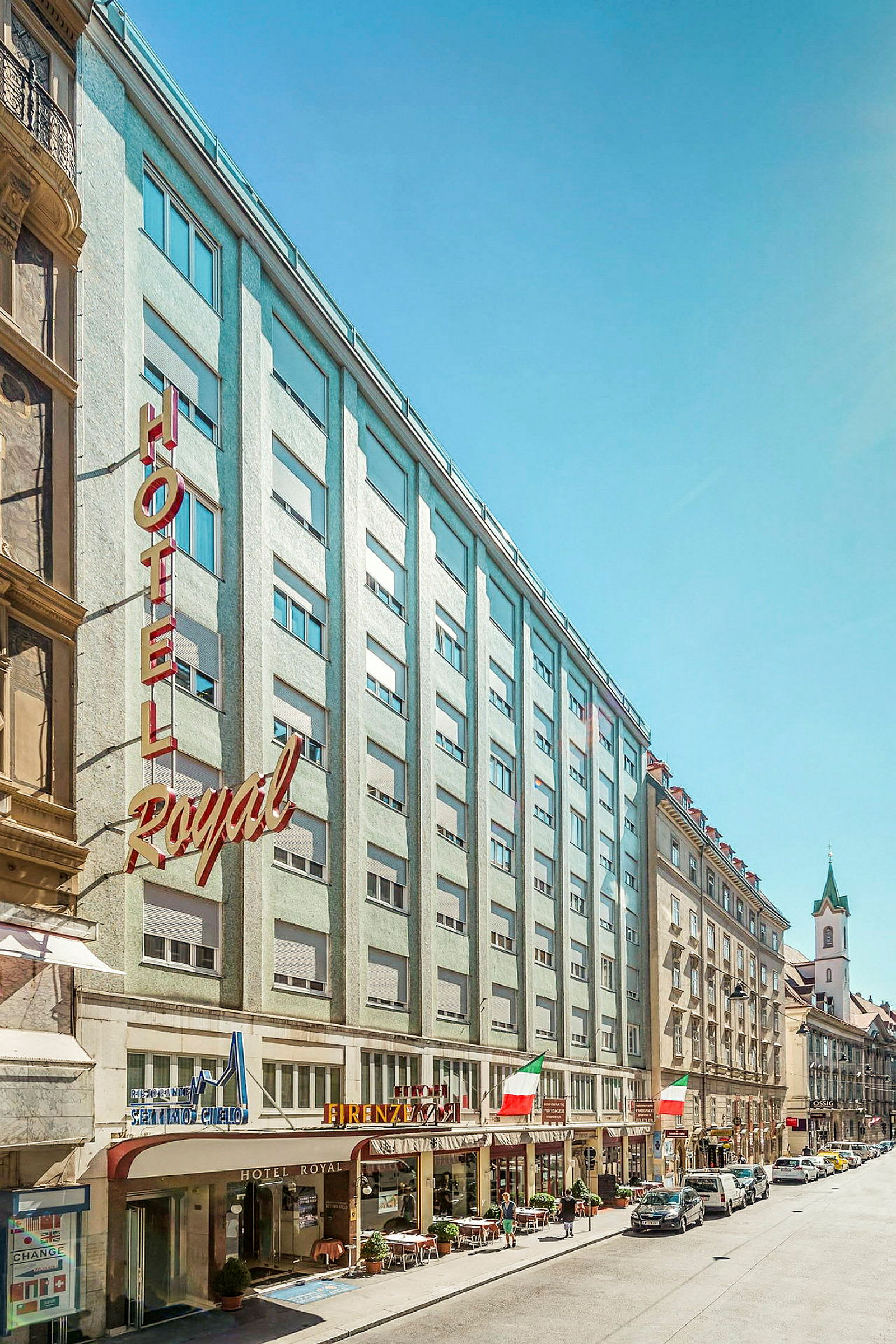 Bild av en stadsgata med hotellfasad och byggnader runt omkring. (AI-genererad text)