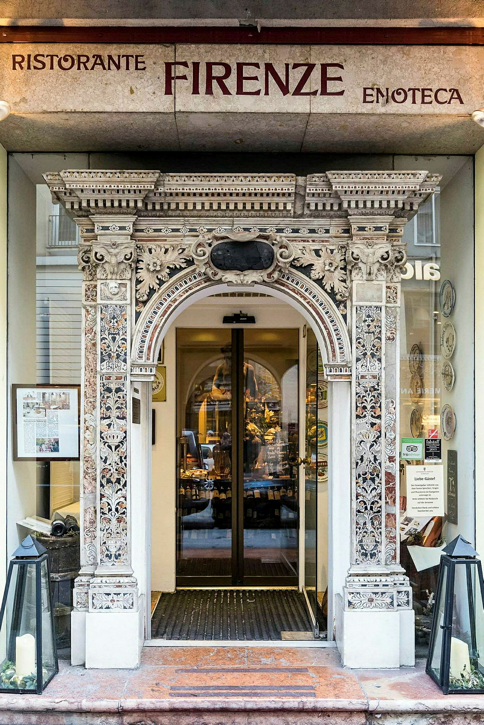 Ingång till restaurang med dekorativt utsmyckad portal och glasdörrar. (AI-genererad text)