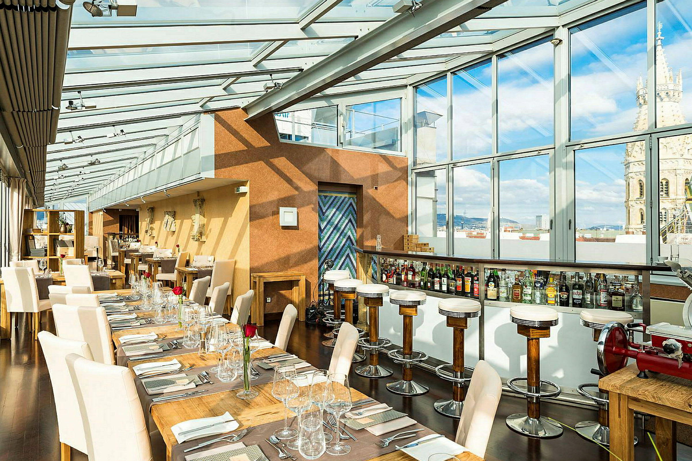 Interiör av en restaurang med glasväggar och tak som släpper in naturligt ljus. Bord och stolar är elegant uppställda med dukar och glas. (AI-genererad text)