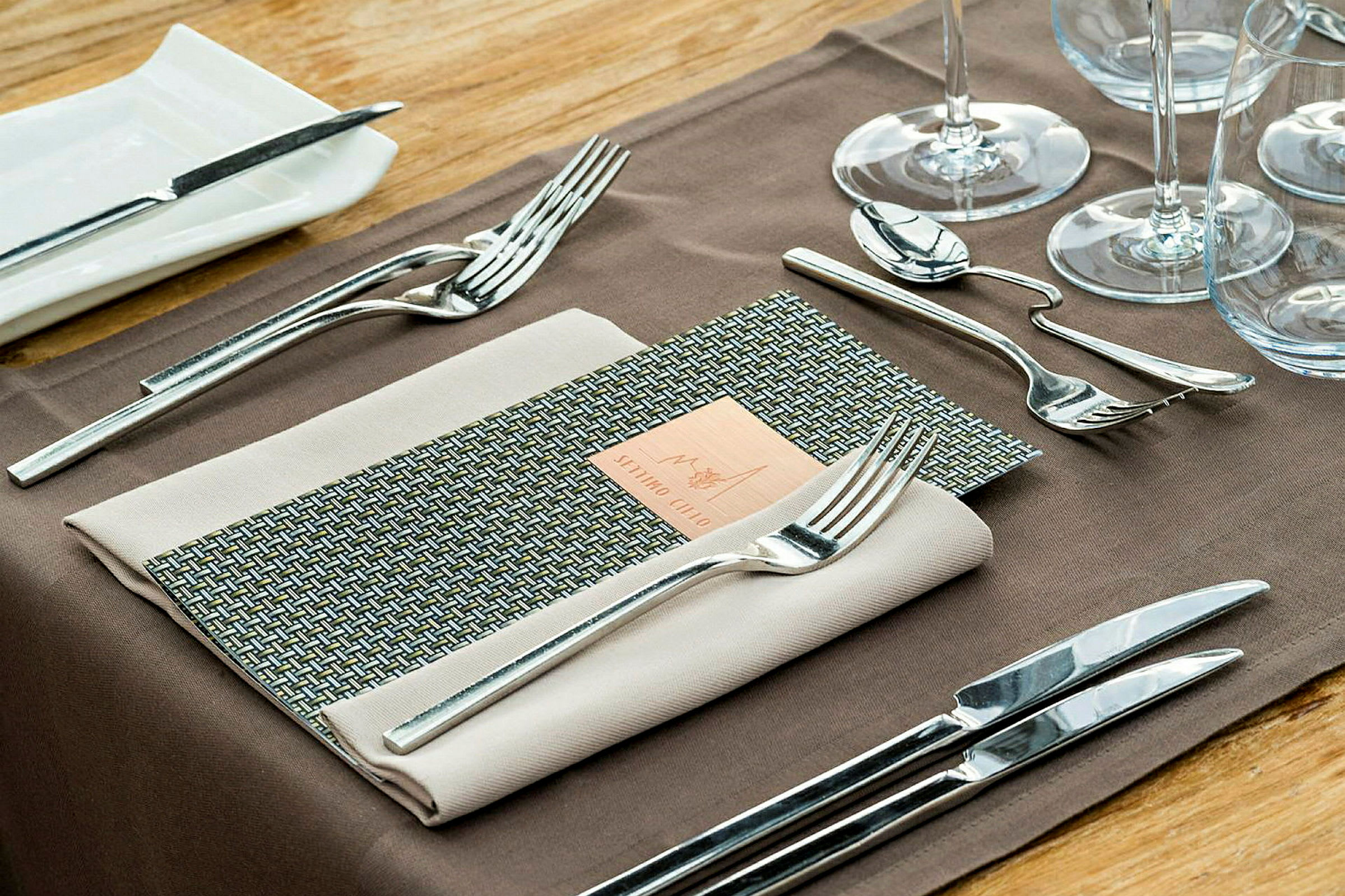 En detaljbild av ett dukat bord med bestick, vinglas och servett. (AI-genererad text)