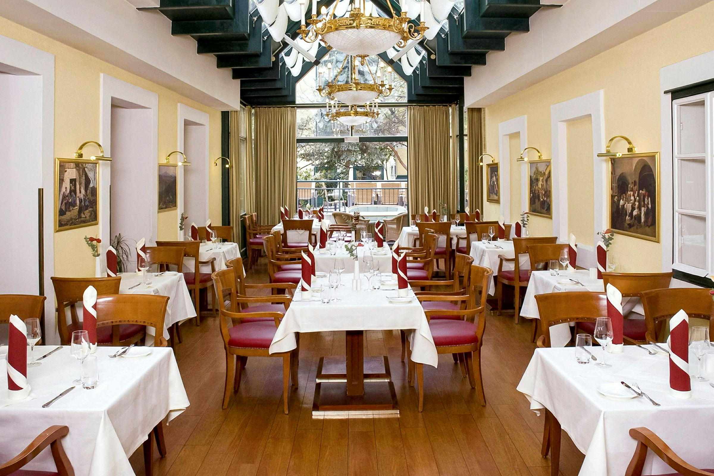 Restaurang med vita dukar på bordsytorna, trästolar med röda sitsar och prydligt vikta servetter. (AI-genererad text)