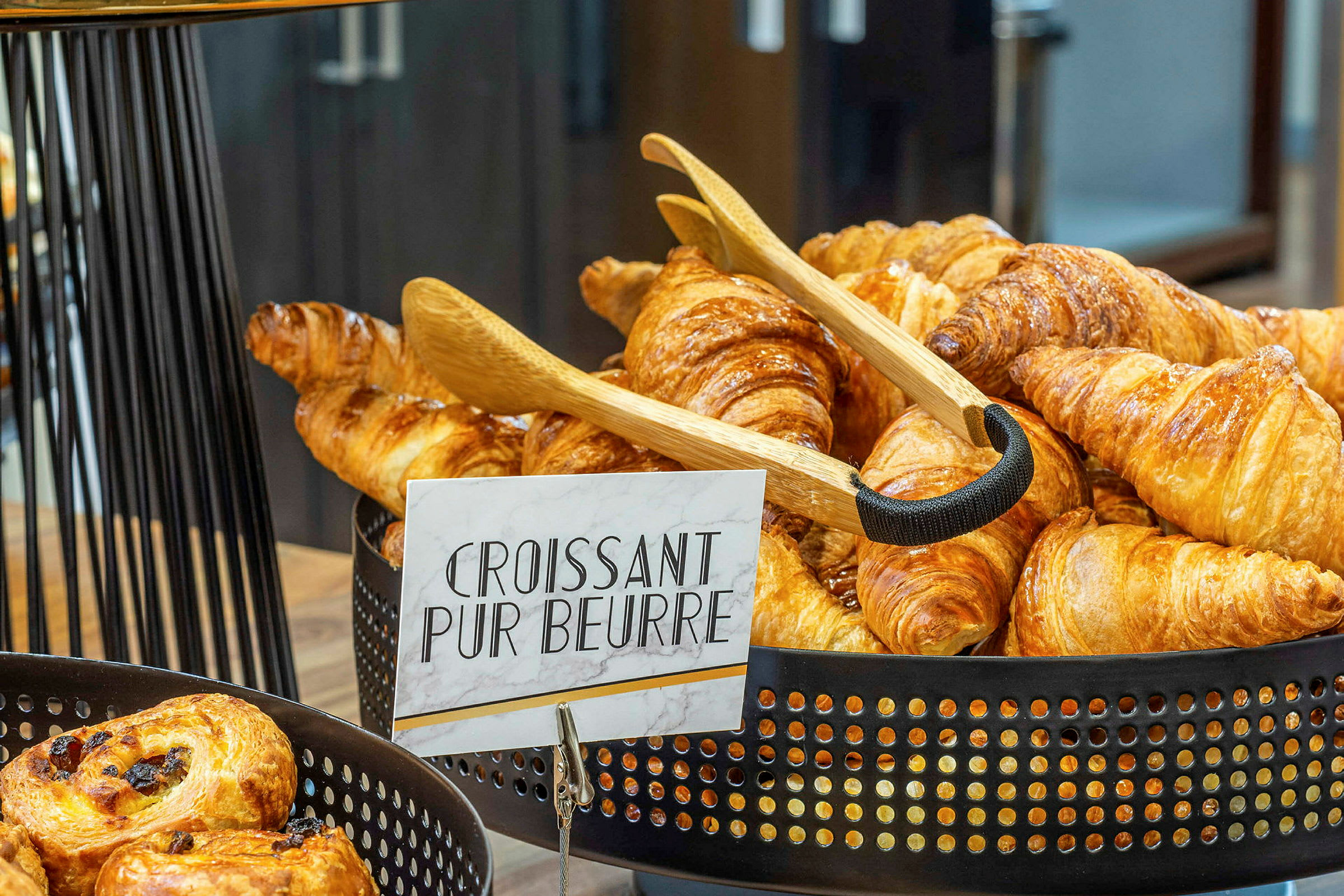 En korg fylld med nybakade croissanter med en skylt som säger 'Croissant Pur Beurre'. (AI-genererad text)