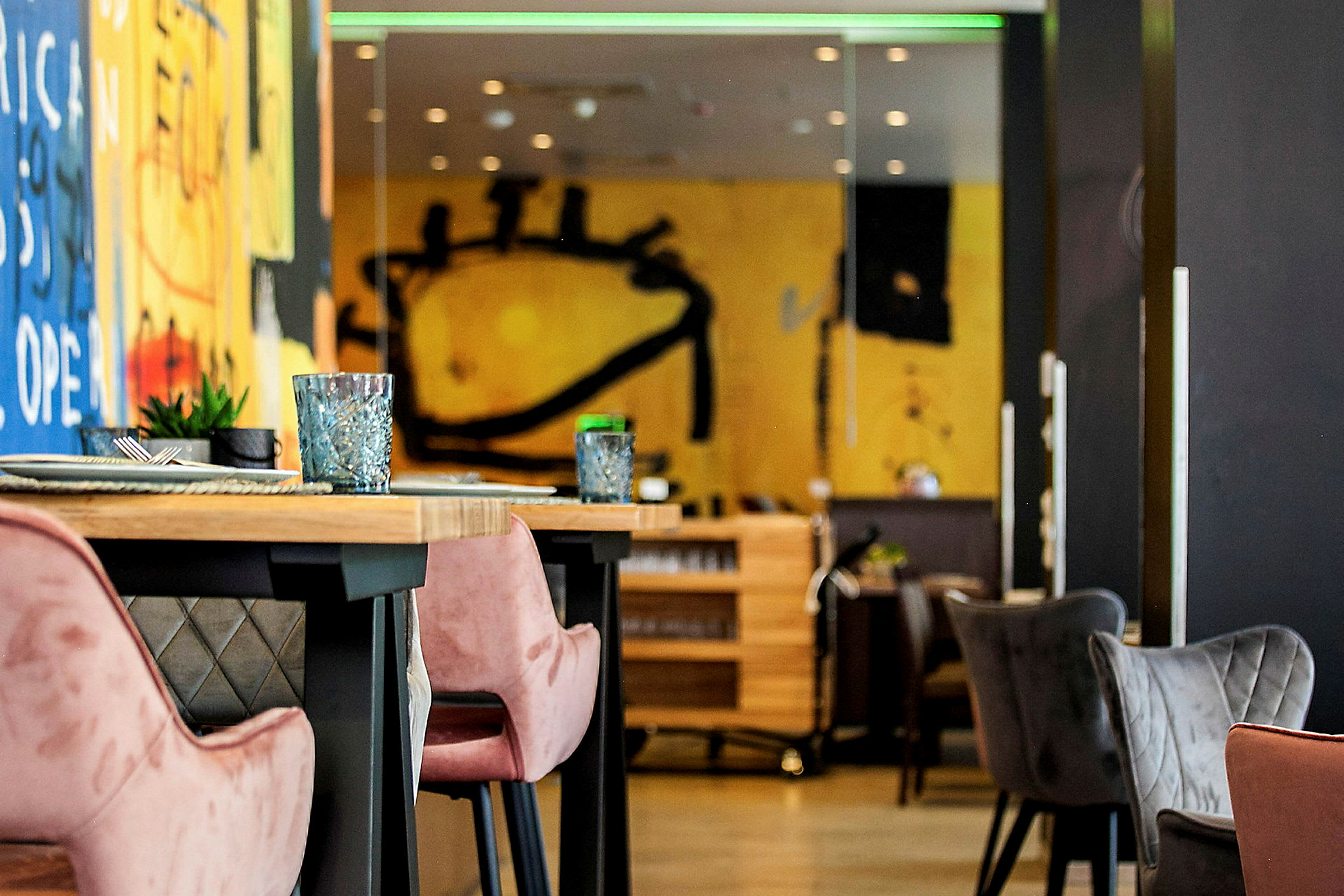 Interiör av en modern restaurang med färgglada väggmålningar och bord med bekväma stolar. (AI-genererad text)