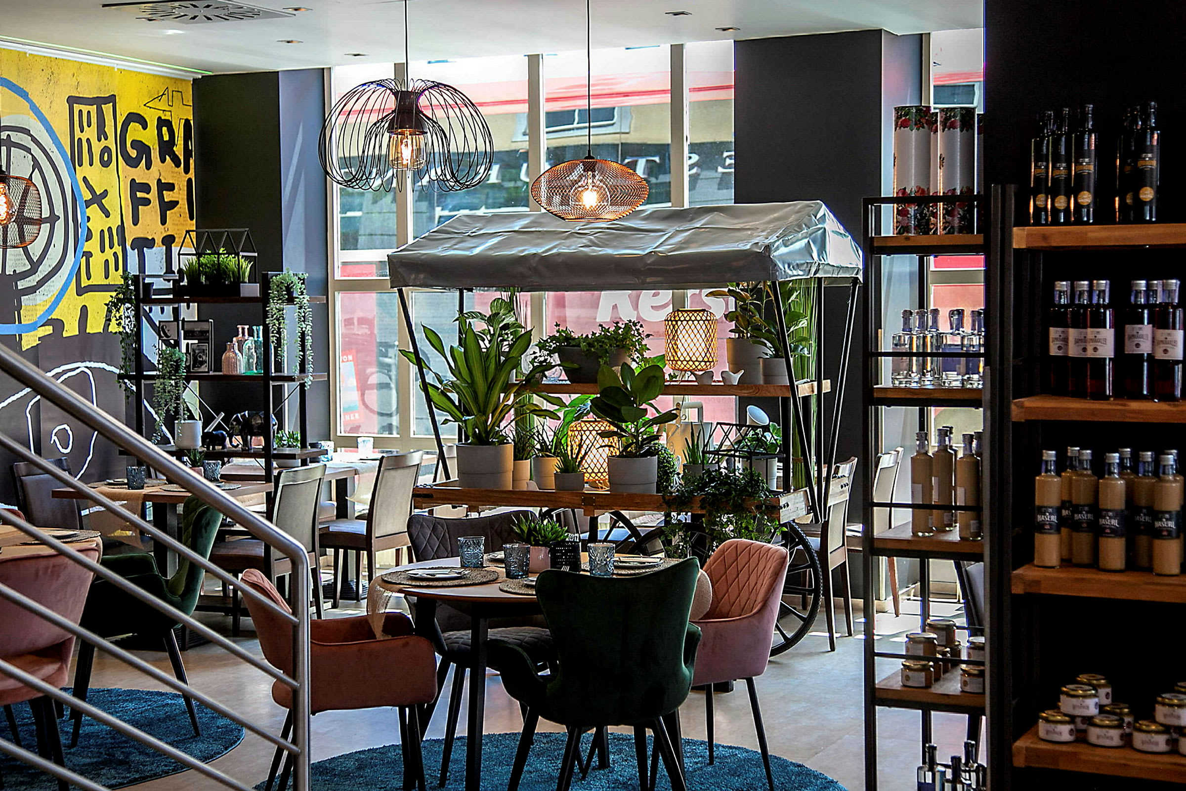 Interiör av ett modernt café med färgstarka stolar, gröna växter och en dekorativ växtvagn. (AI-genererad text)