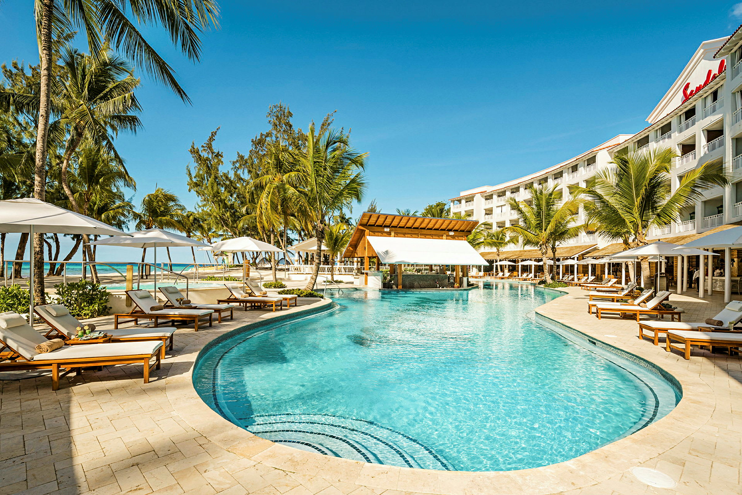 Poolområde vid Sandals hotell med solsängar och palmer. (AI-genererad text)
