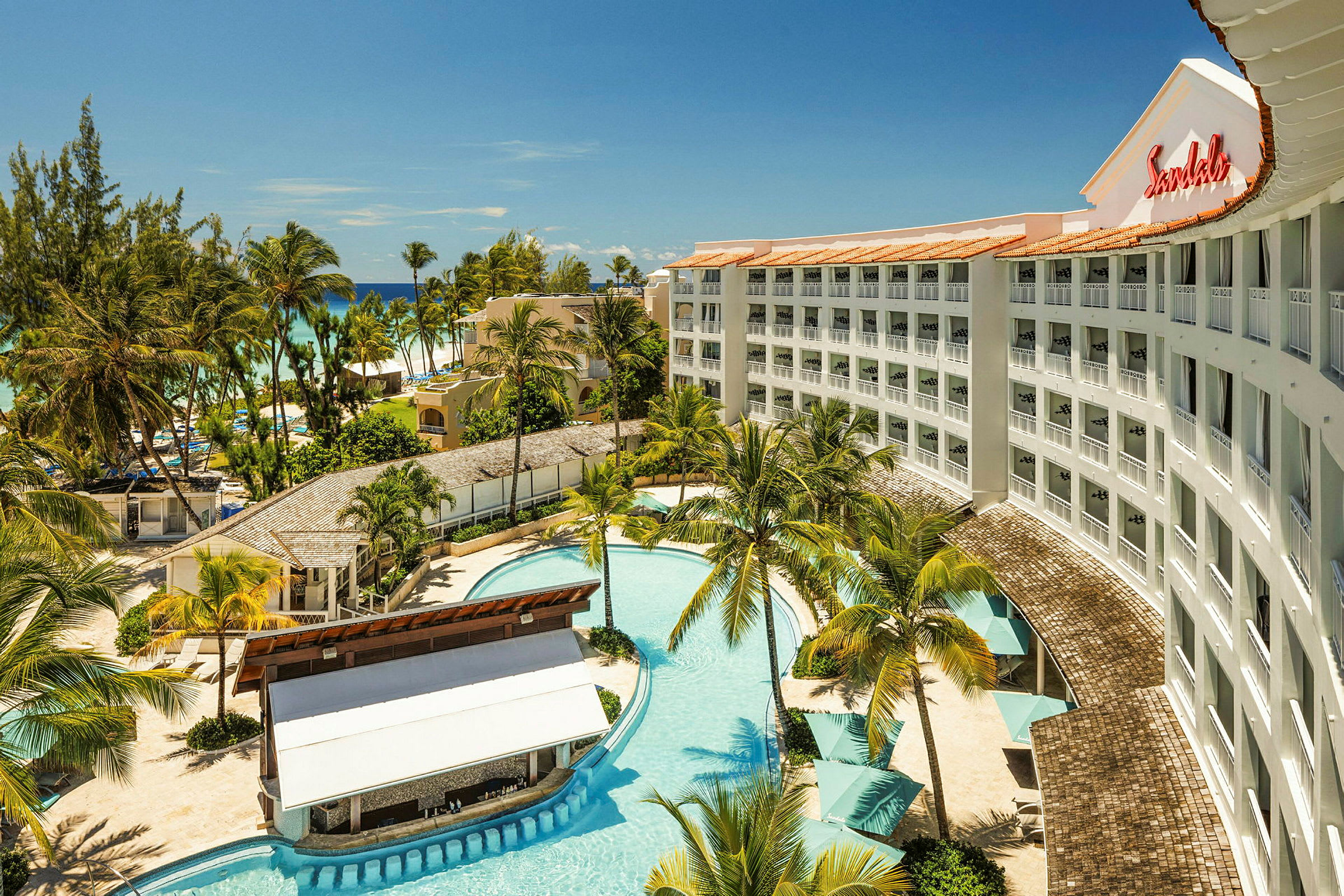 Ett hotell med pool, omgivande palmer och närliggande strand. (AI-genererad text)