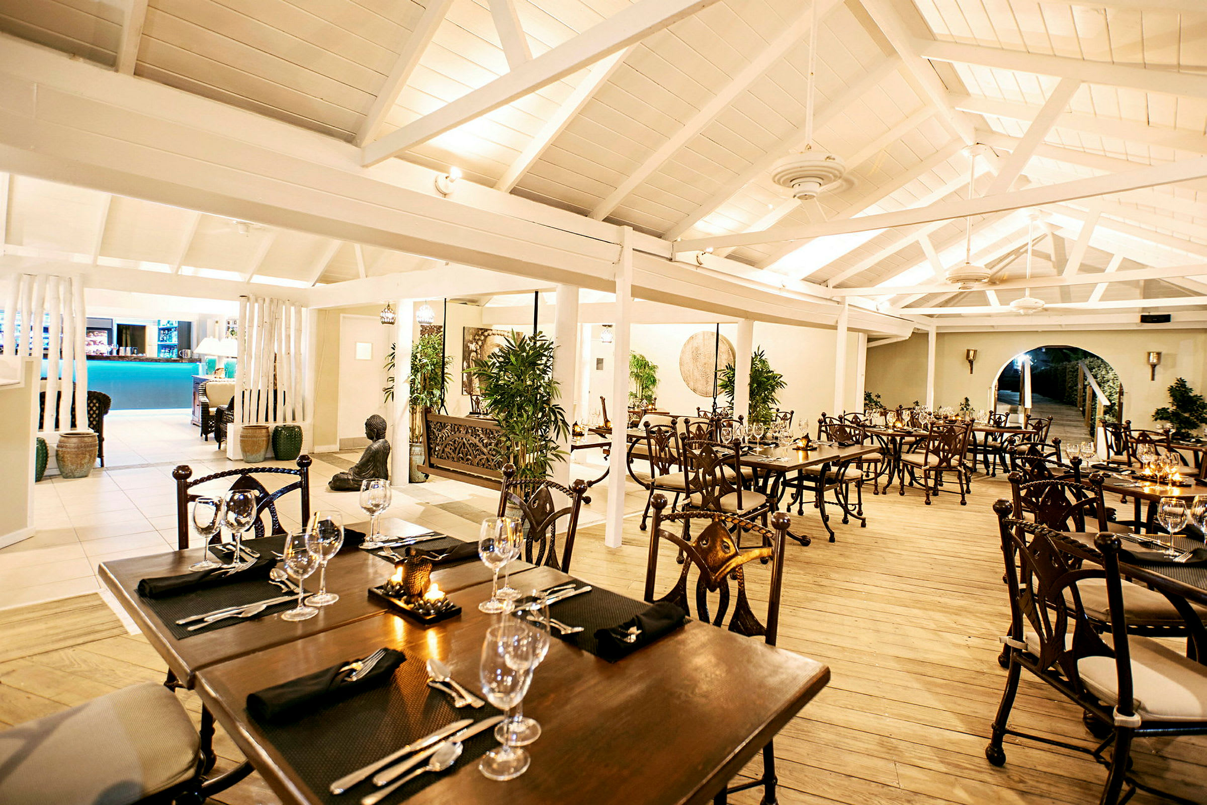 Interiören av en elegant restaurang med träbord, stolar och dekorationer. (AI-genererad text)