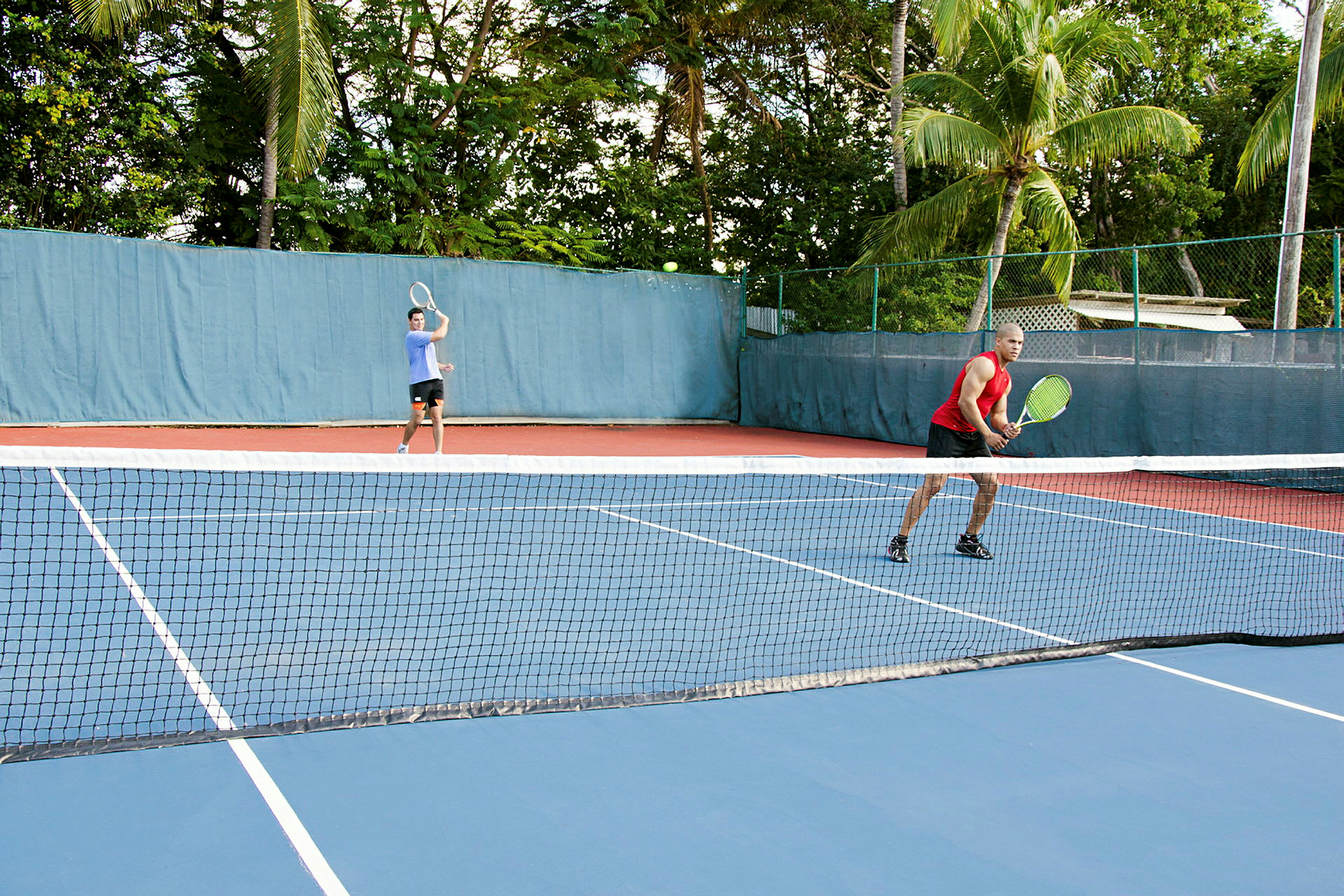 Två personer spelar tennis på en utomhusbana. (AI-genererad text)