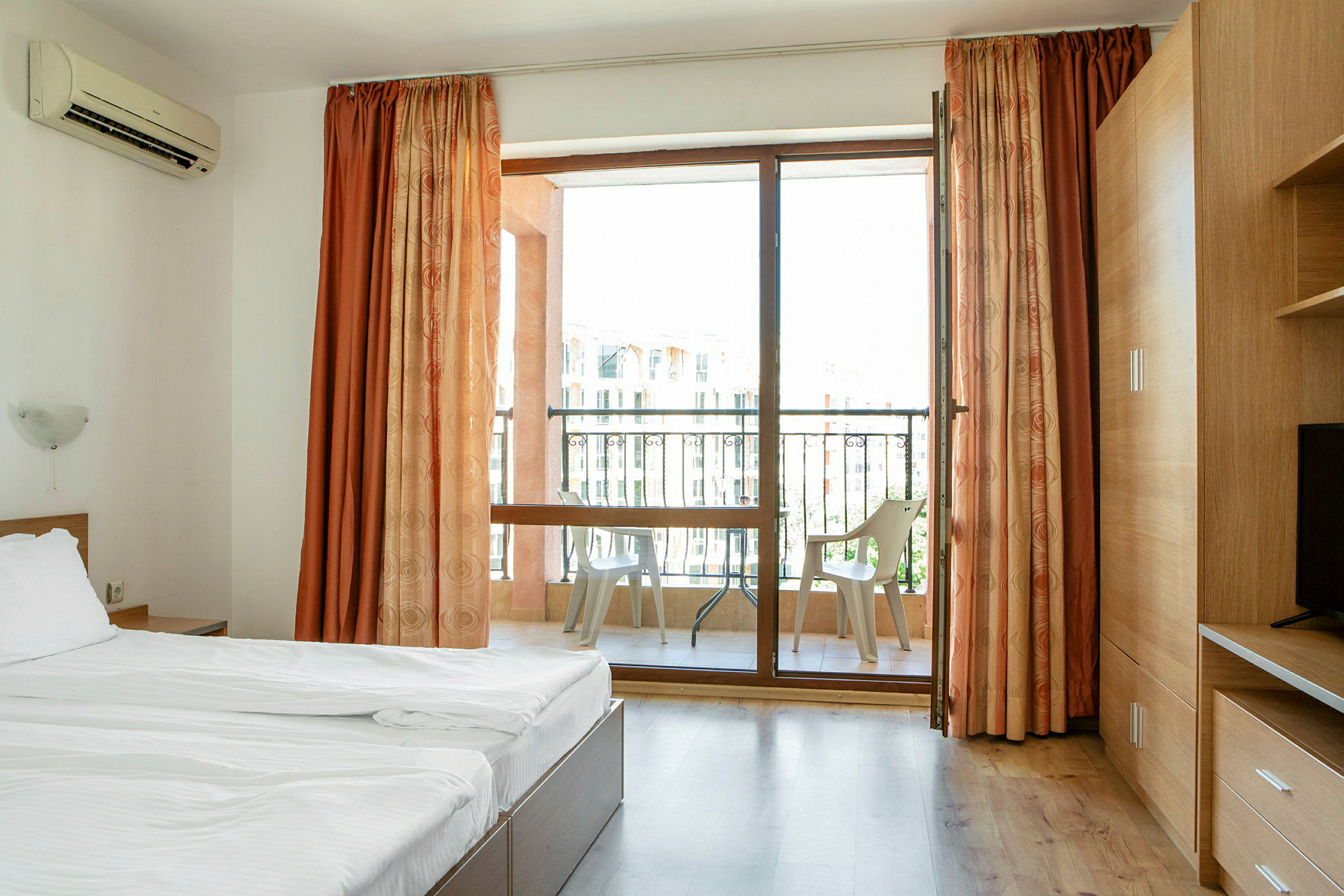 Ett hotellrum med en säng och en balkong med stolar. (AI-genererad text)