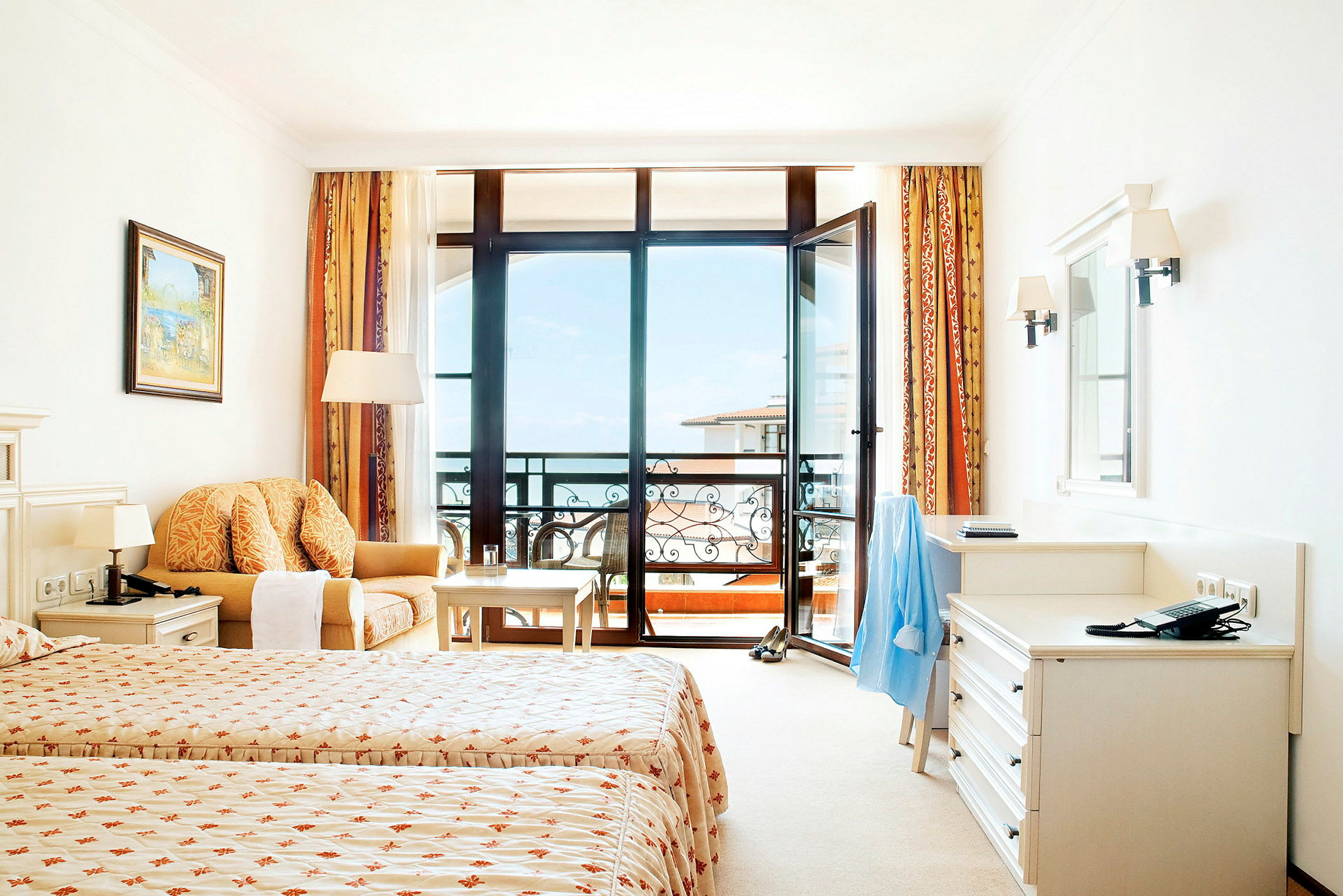 Ett hotellrum med två enkelsängar, en soffa, ett skrivbord och en balkong med utsikt. (AI-genererad text)