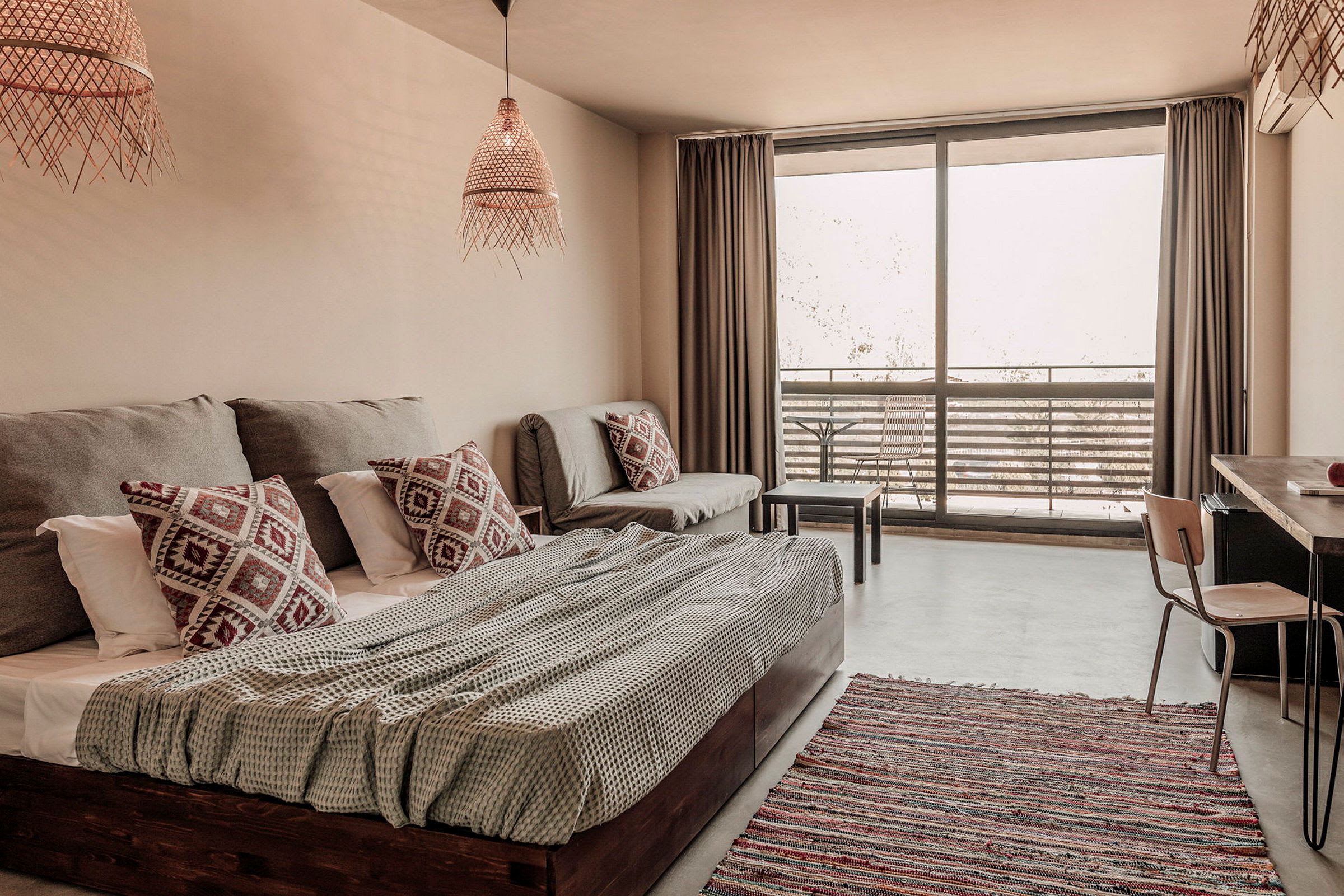 Ett ljust och modernt hotellrum med säng, soffa och en balkong med utemöbler. (AI-genererad text)