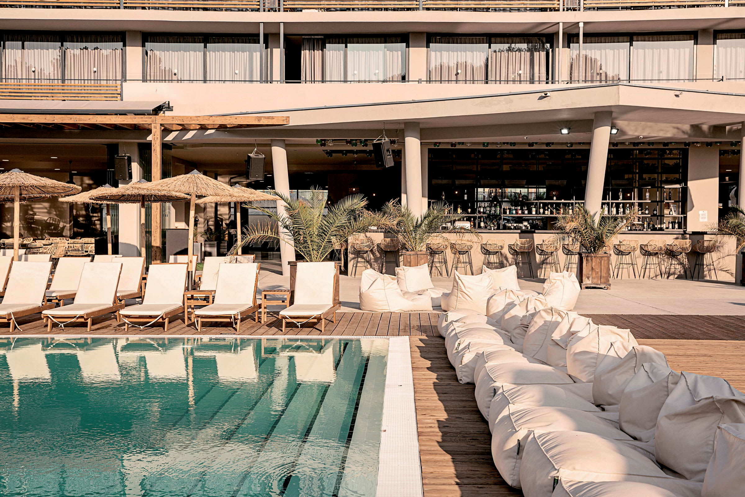 En pool med solstolar och säckstolar vid ett hotellområde. (AI-genererad text)