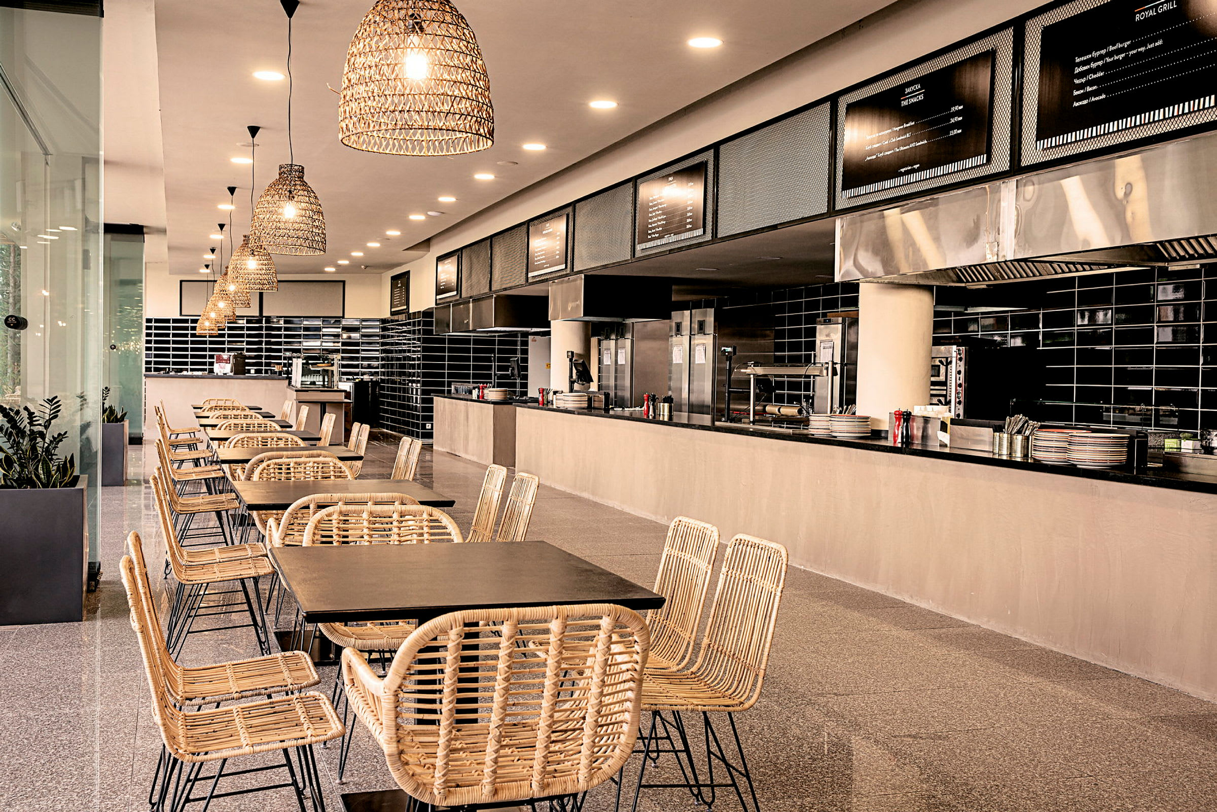 Modern restaurangmiljö med naturfärgade stolar och bord framför ett öppet kök. (AI-genererad text)