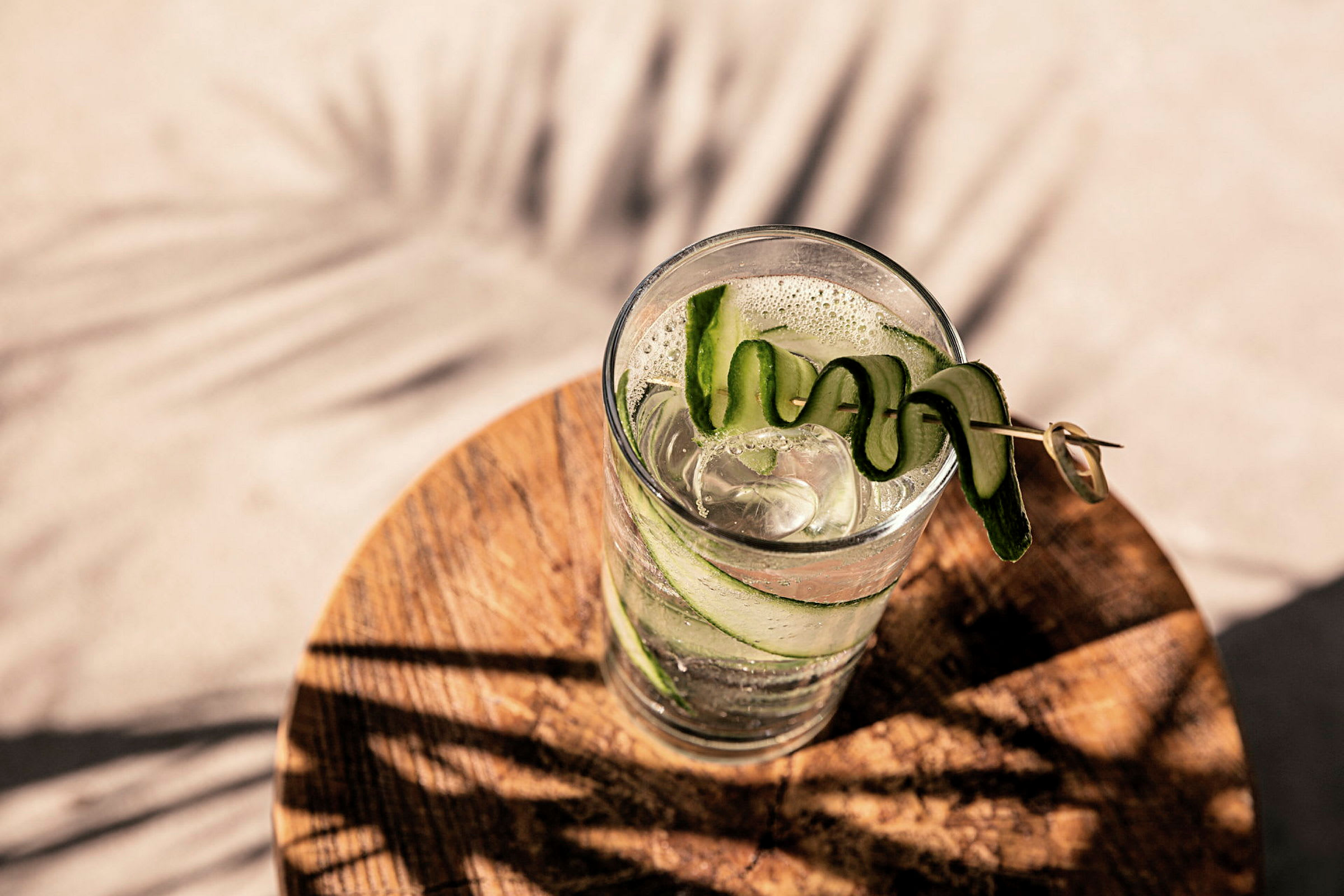 Ett glas med is och dekorativ gurka på ett träbord. (AI-genererad text)