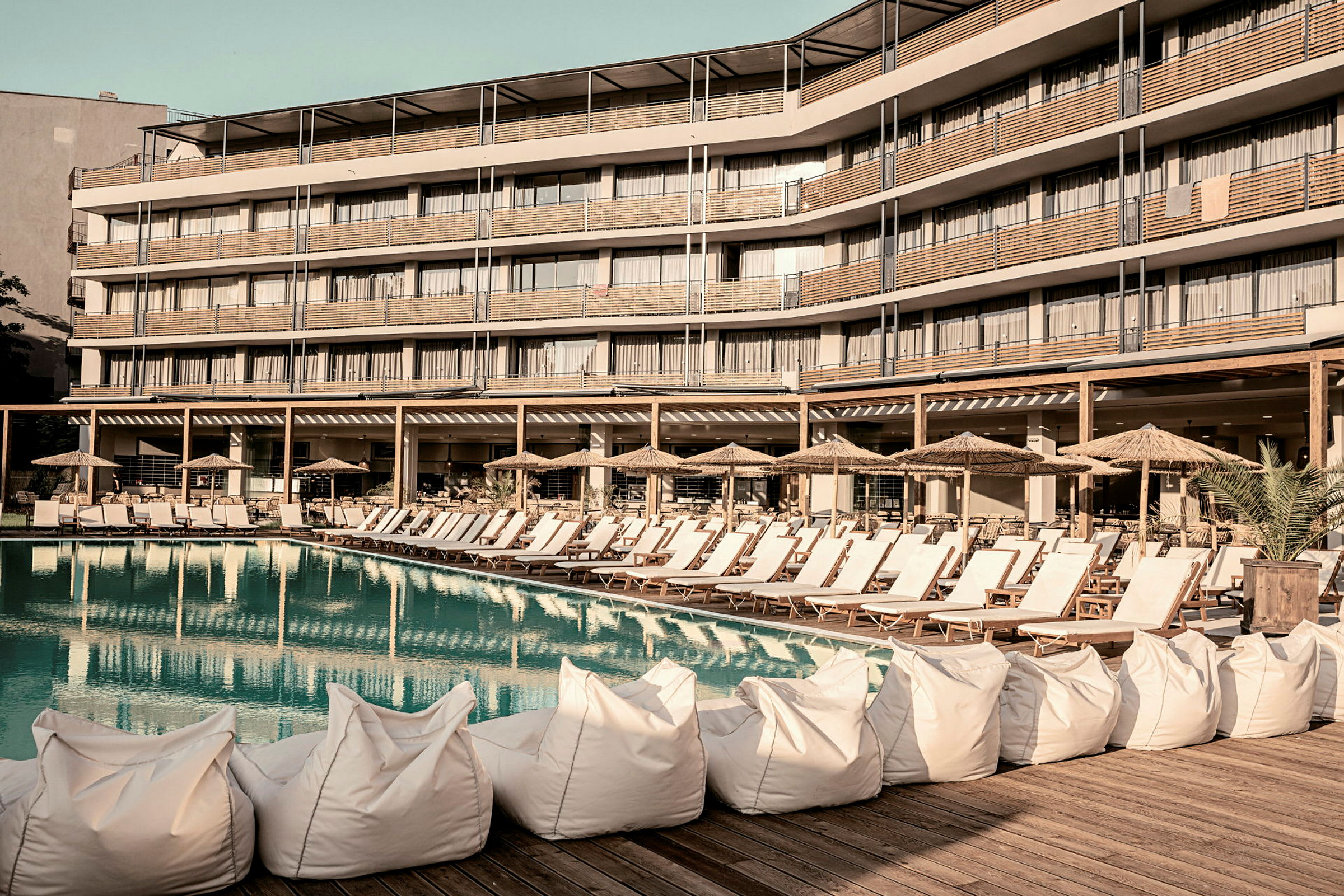 Solstolar och parasoller vid en pool framför ett hotell. (AI-genererad text)