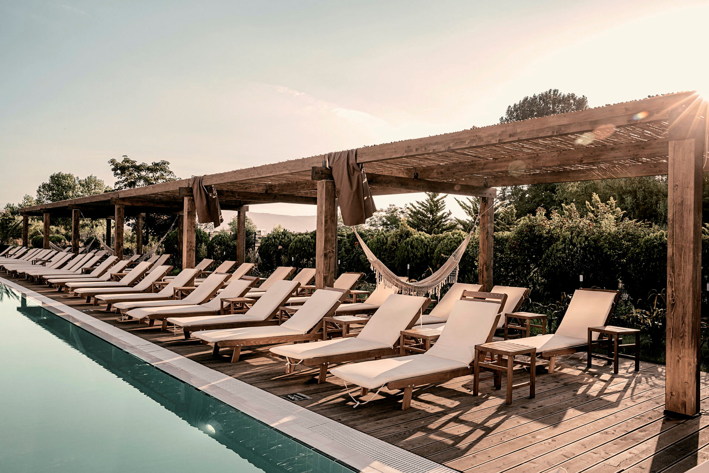 Solstolar vid en pool under träpergola. (AI-genererad text)