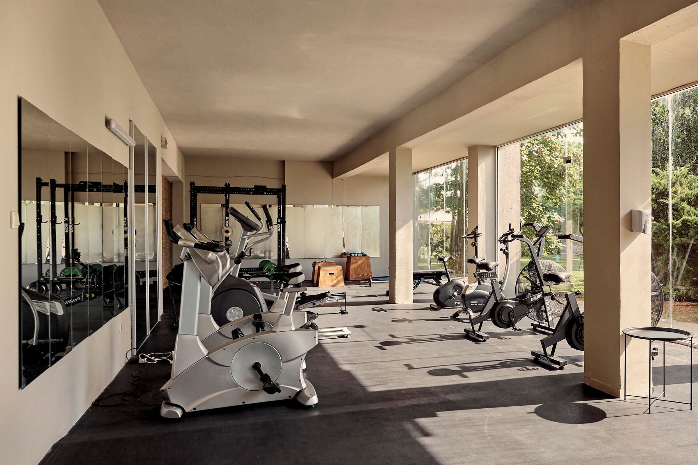 Ett gym med träningsmaskiner och stora fönster som släpper in naturligt ljus. (AI-genererad text)