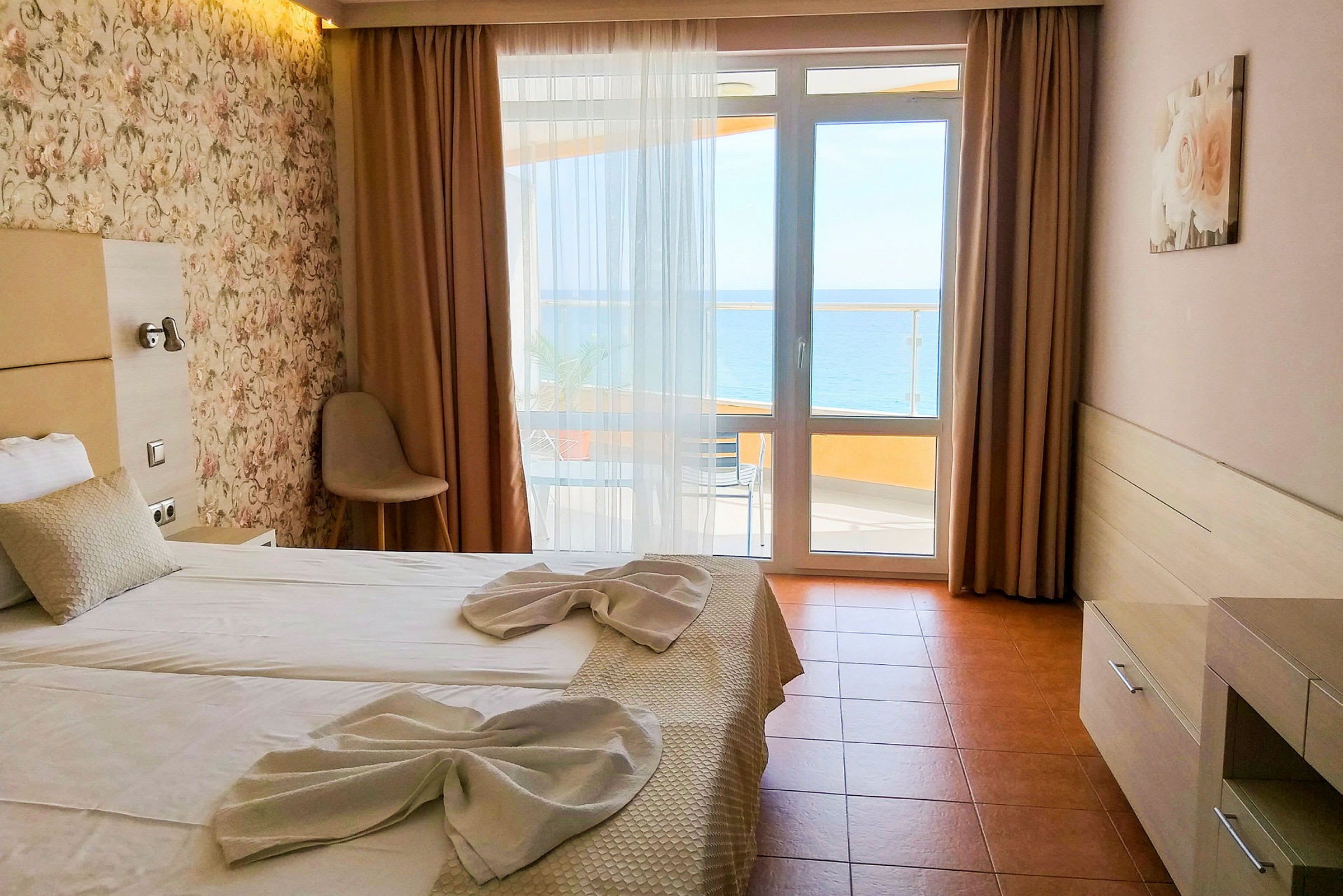 Ett hotellrum med en dubbelsäng bäddad med vita lakan och dekorerad med handdukar. Det finns ett fönster med utsikt mot havet. (AI-genererad text)