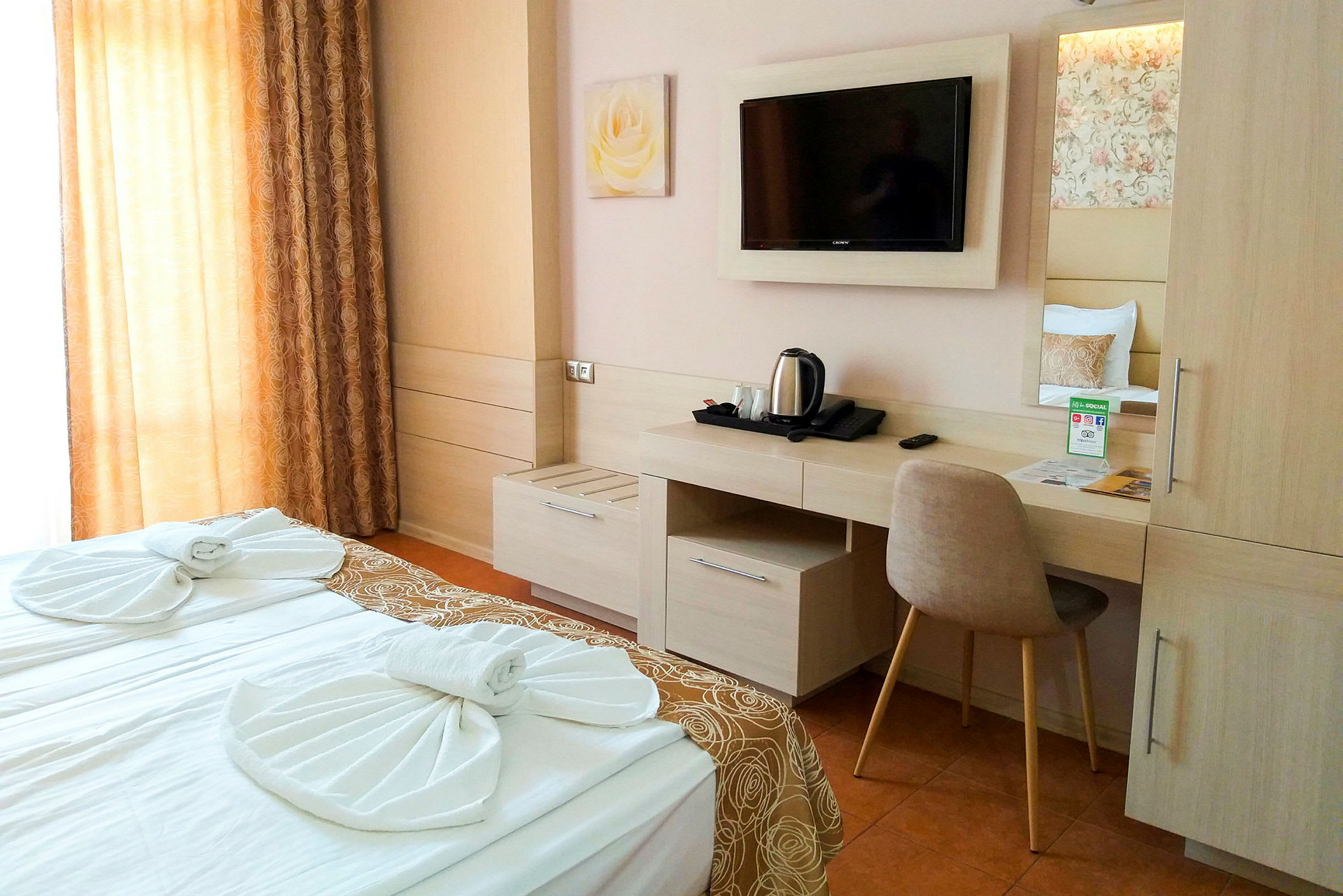 Hotellrum med dubbelsäng, skrivbord och väggmonterad TV. (AI-genererad text)