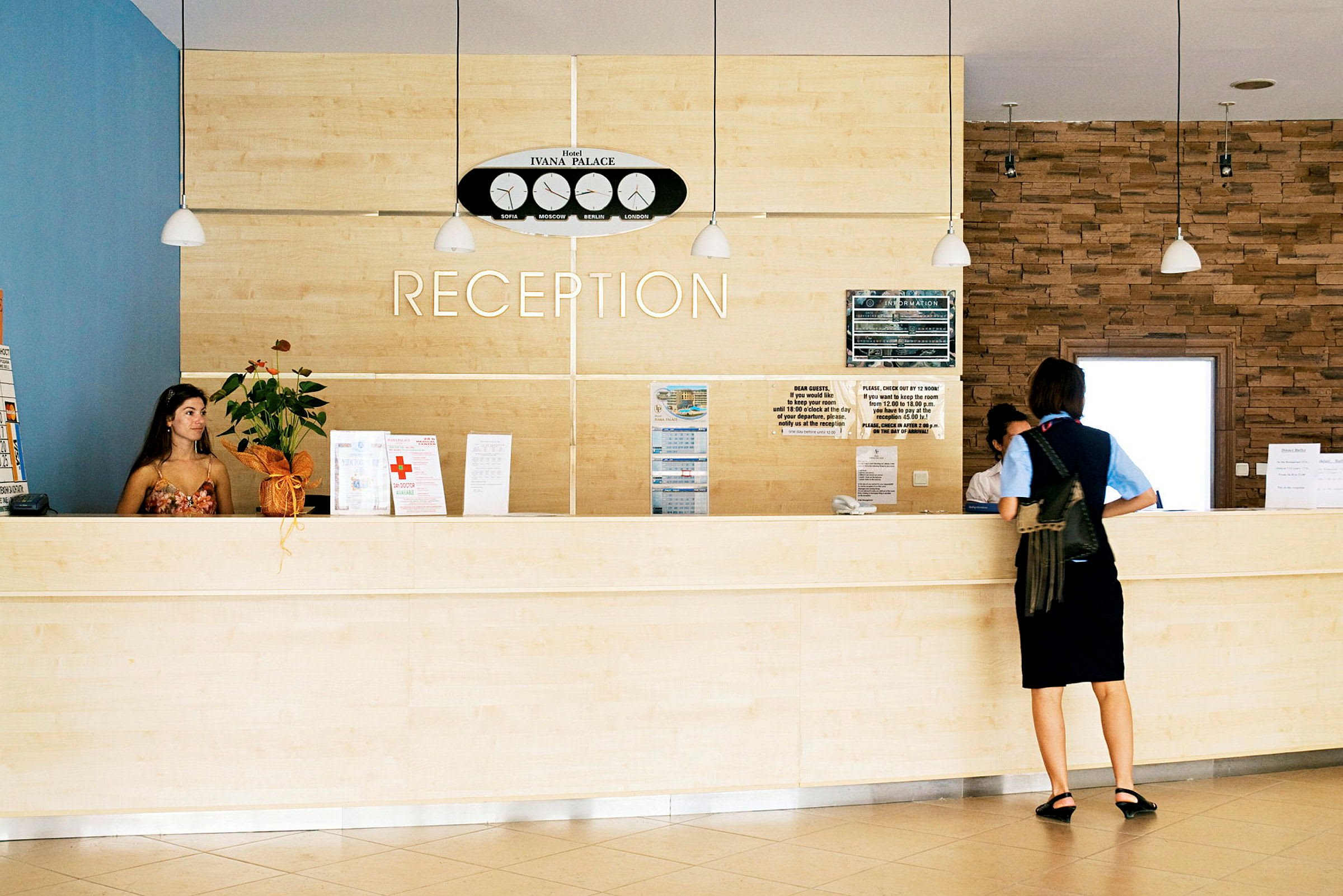 Reception med ljus träinredning och en person som står framför disken. (AI-genererad text)
