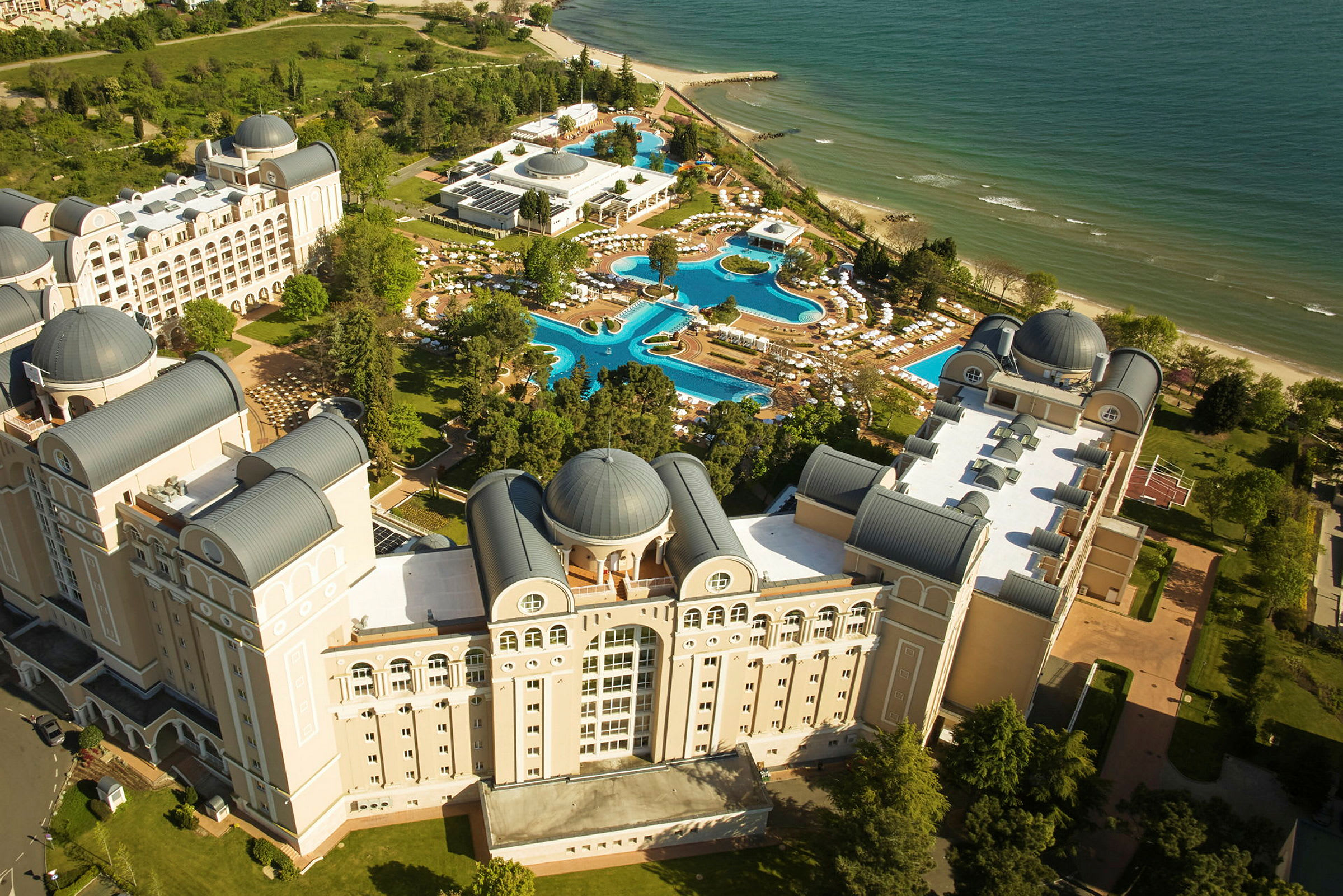 Vy från ovan av ett hotellkomplex med pooler och strand. (AI-genererad text)