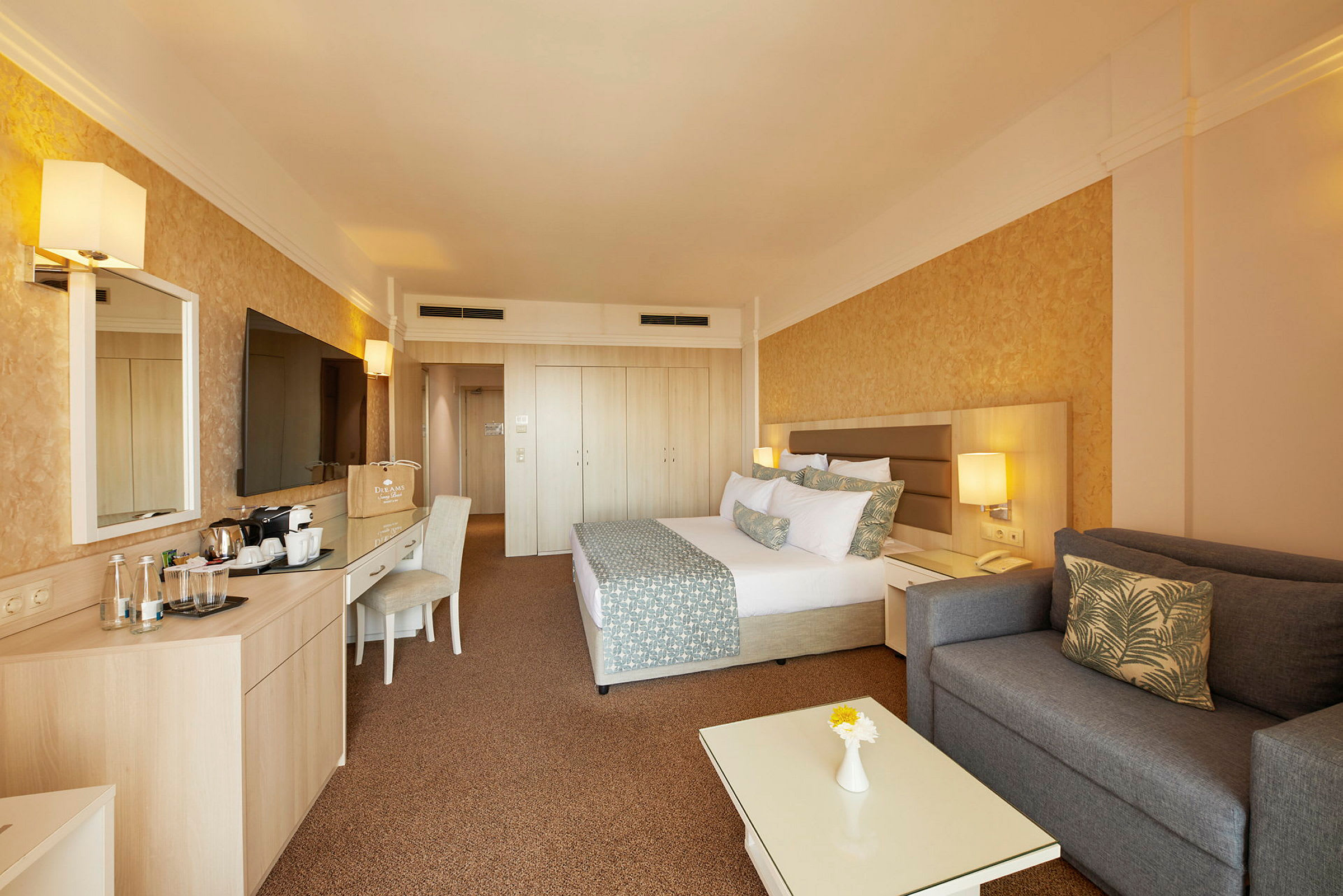 Ett hotellrum med en säng, en soffa, ett bord och en TV. (AI-genererad text)