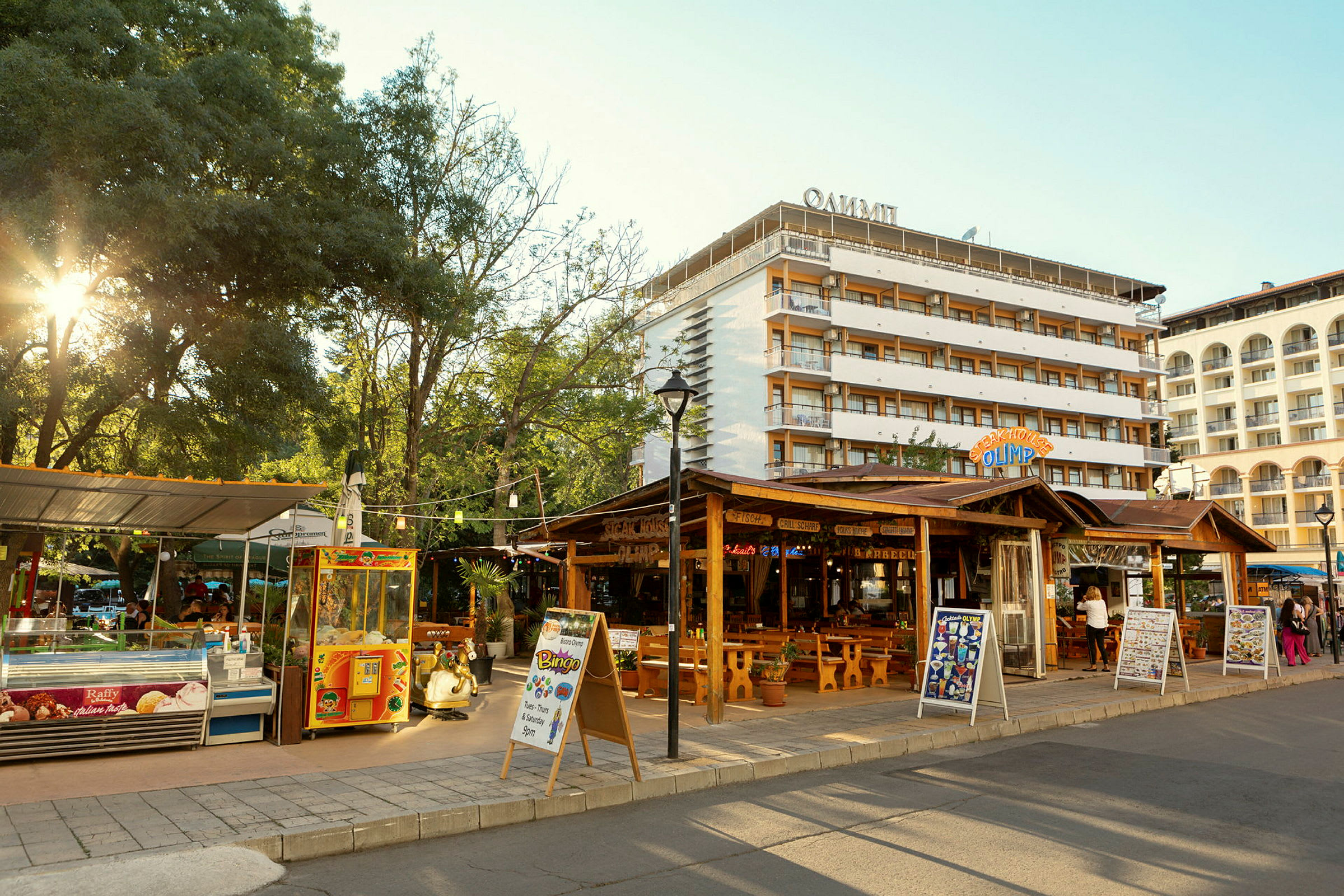 En gata med restauranger och butiker, samt hotellbyggnader i bakgrunden. (AI-genererad text)