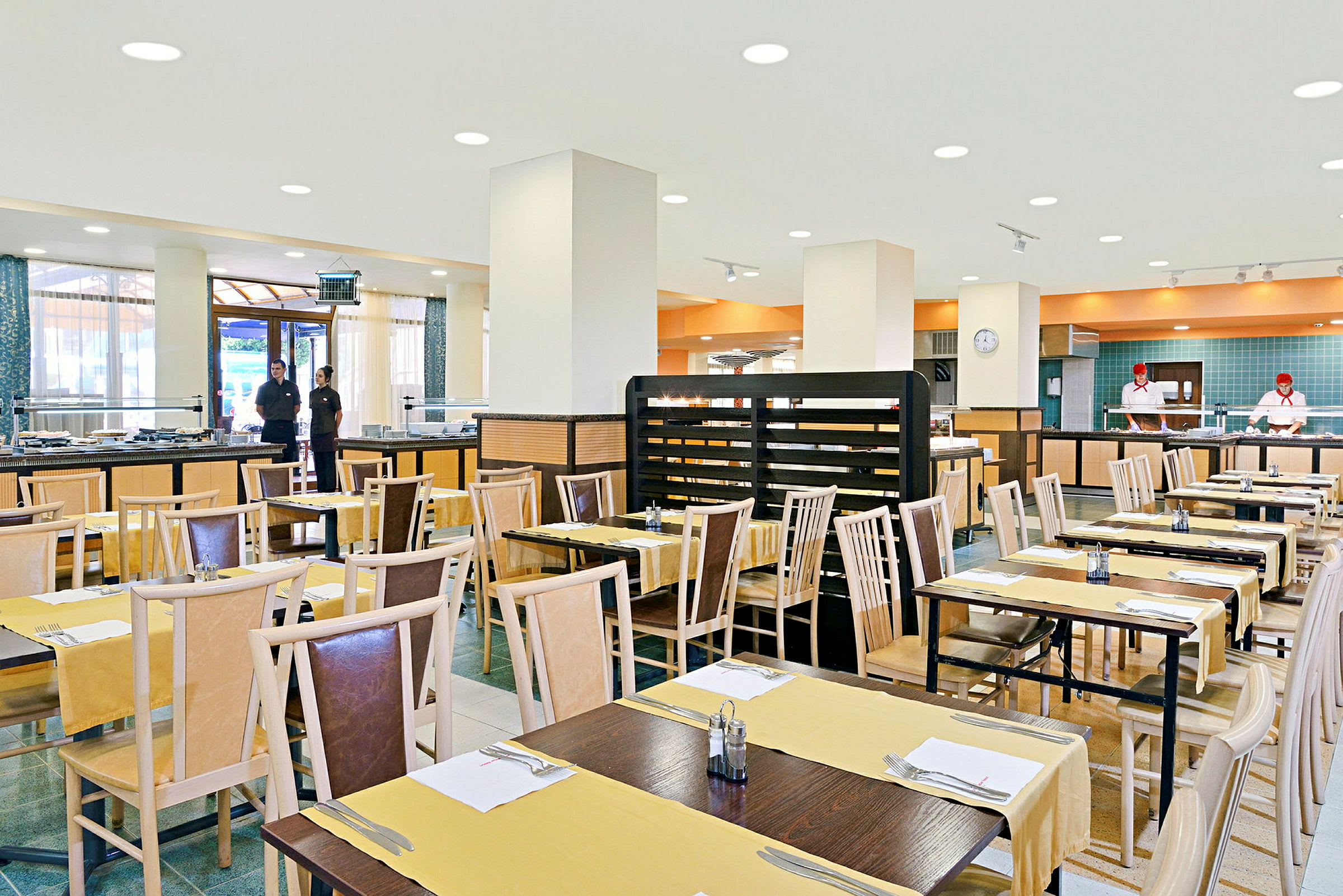 Restaurang med uppställda bord och stolar, färdigdukade för gäster, i en ljus och rymlig matsal. (AI-genererad text)